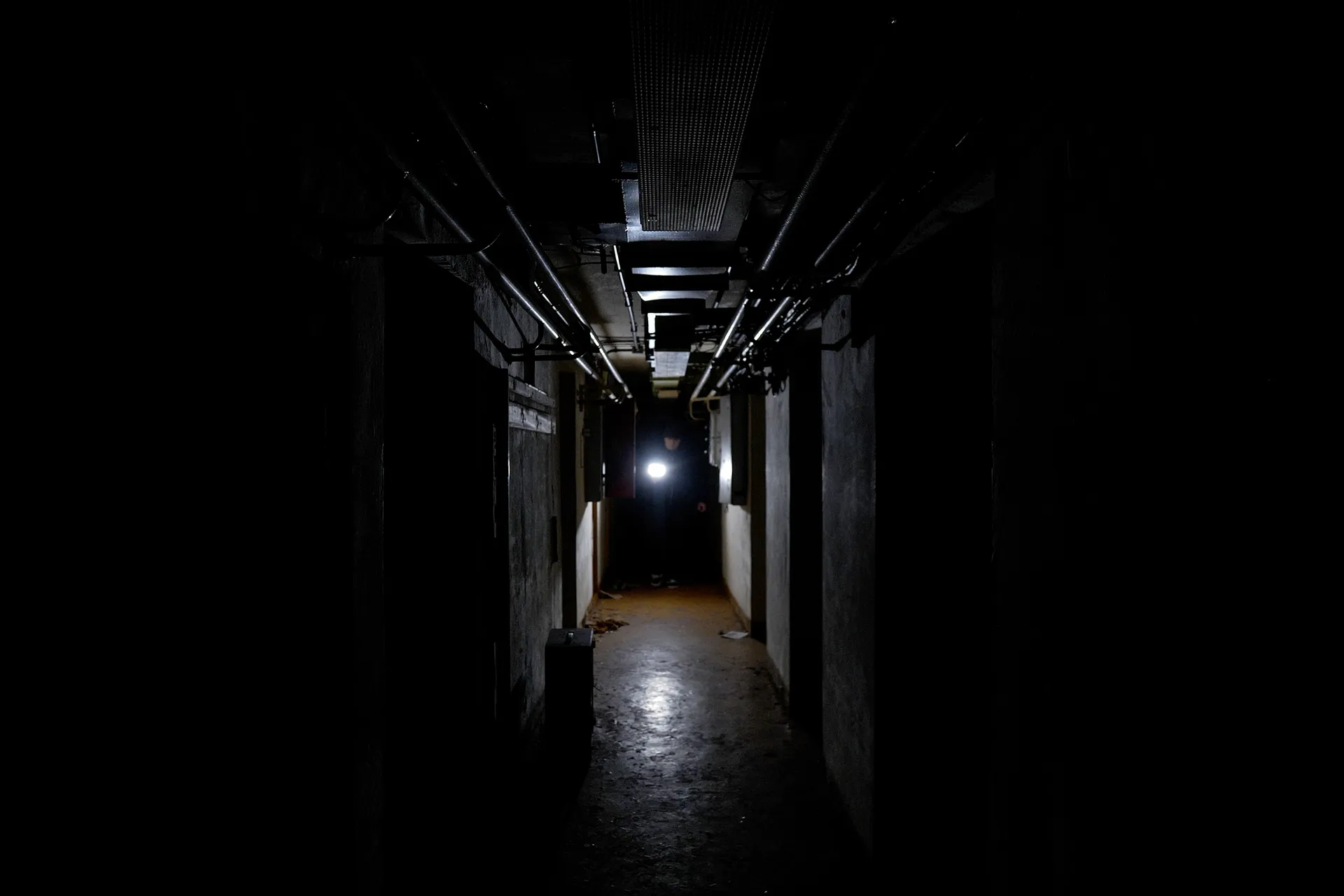 Simon stands with a torch at the far end of the bunker, his path illuminated. 