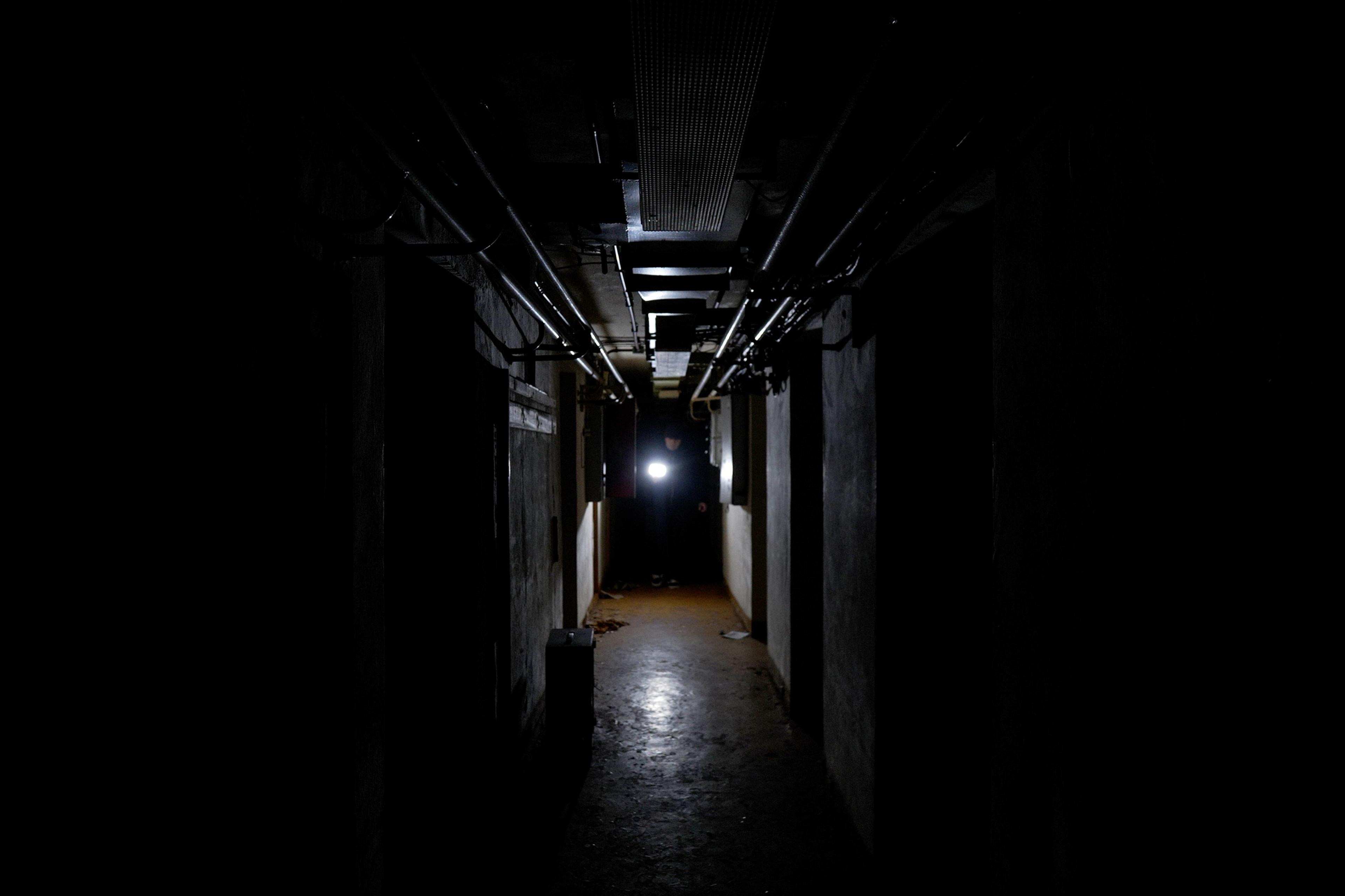 Simon stands with a torch at the far end of the bunker, his path illuminated. 