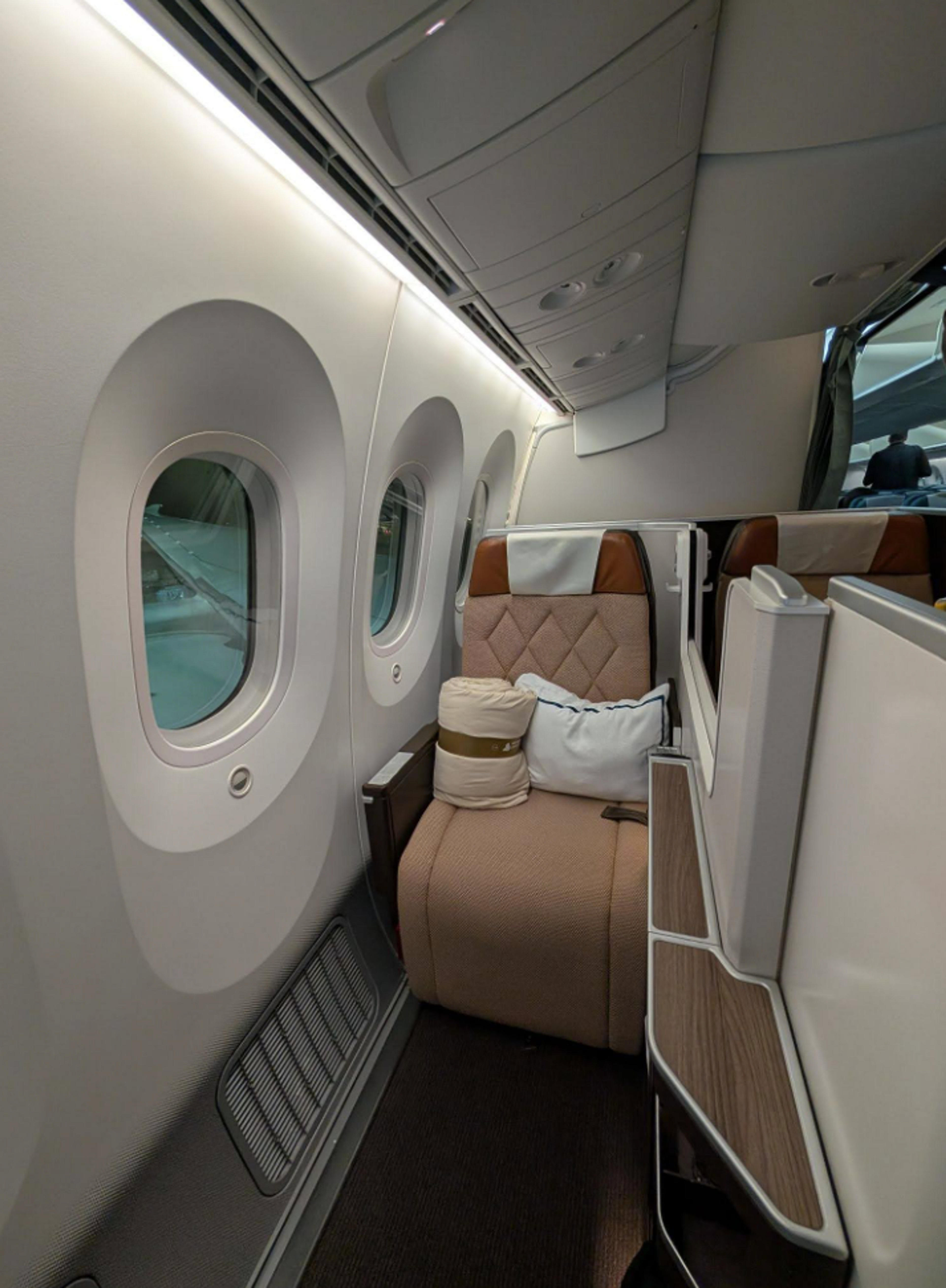 A luxurious airline business class seat inside an aircraft cabin.