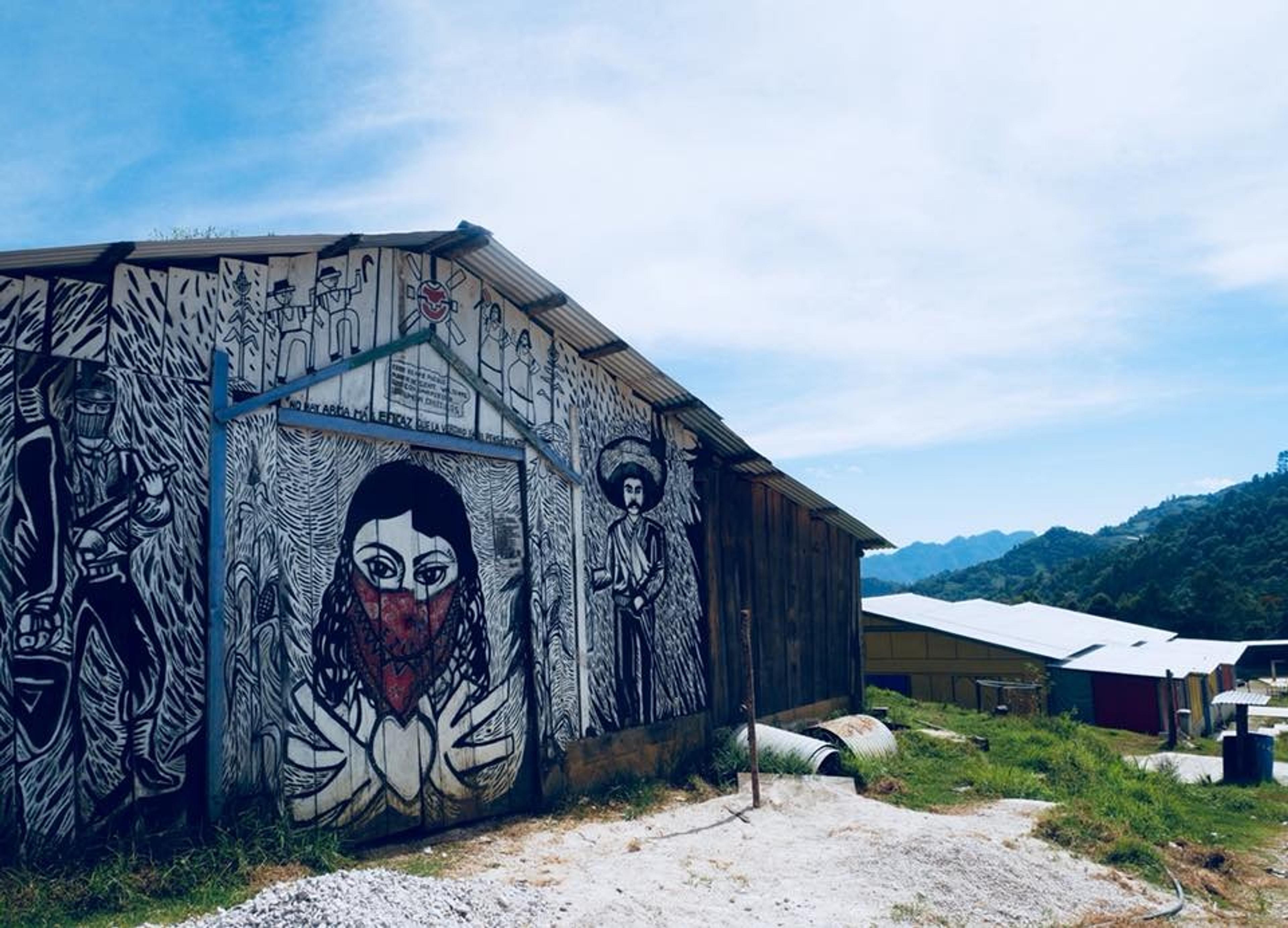 Murals featuring activist imagery adorn a building in the scenic hills of Chiapas, Mexico.