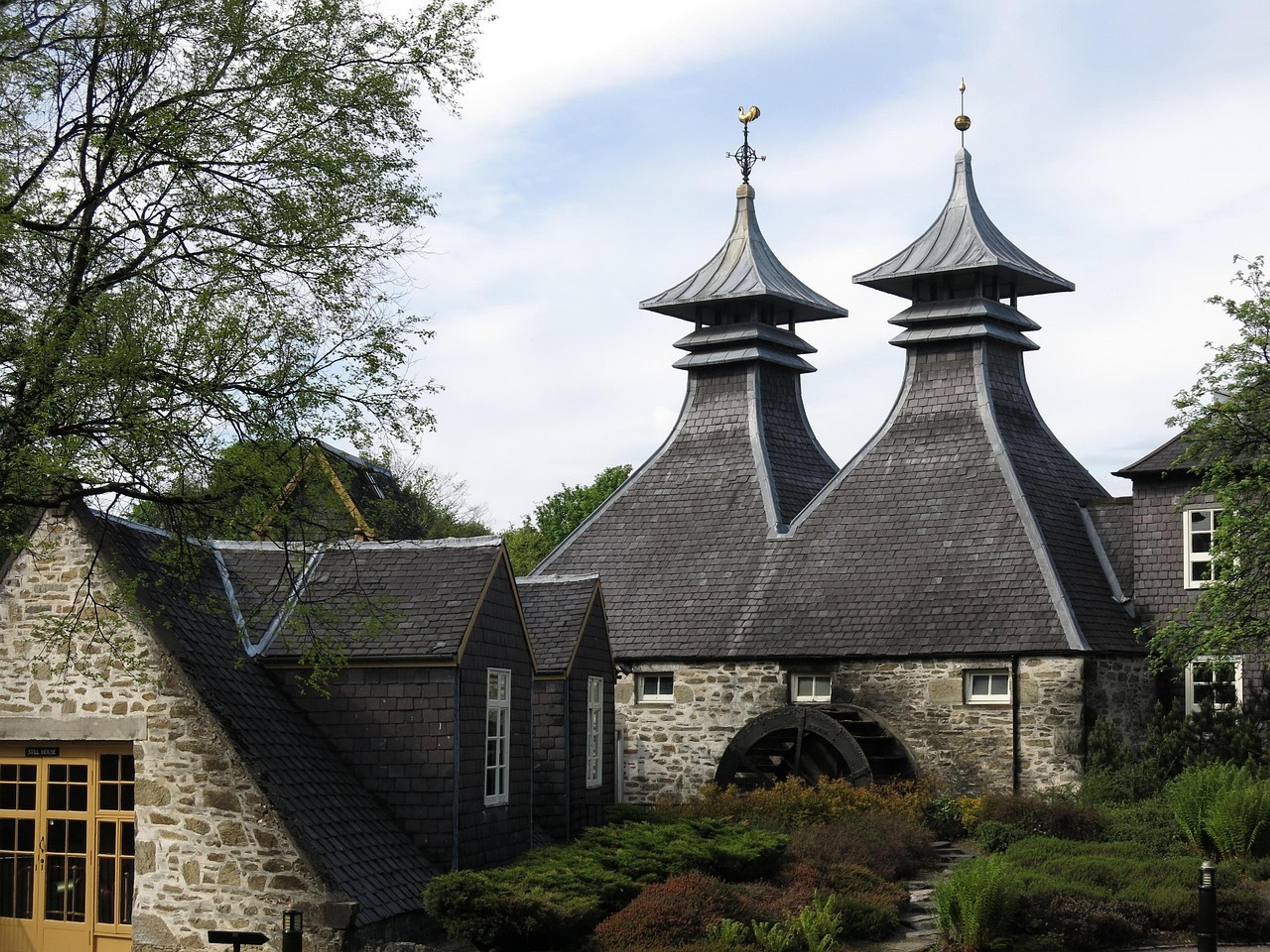 Traditional pagoda-like roofs adorn a historic distillery building surrounded by greenery in Speyside, Scotland.