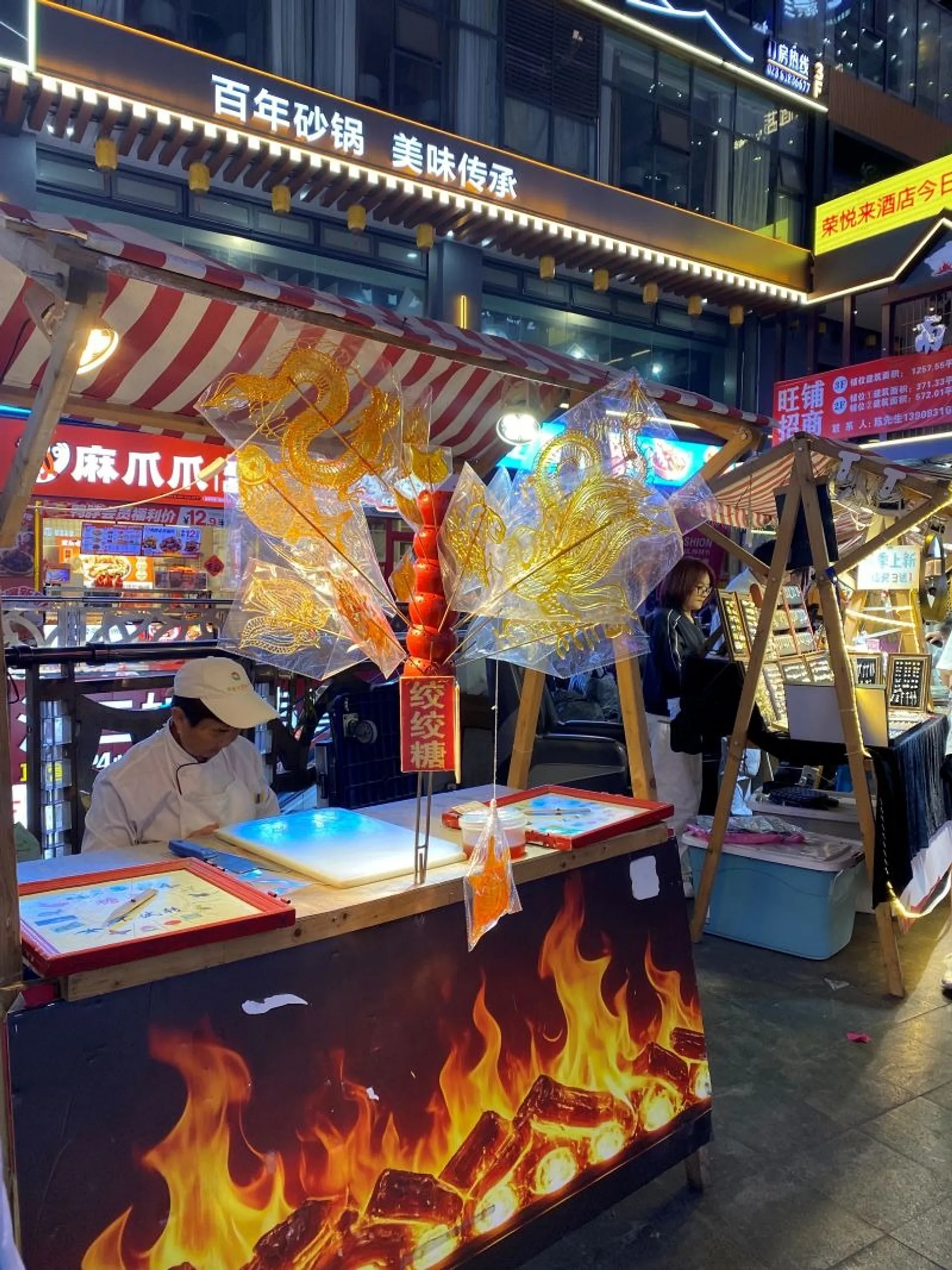 A lively street food stall is illuminated at night in a bustling market in Chengdu, China.