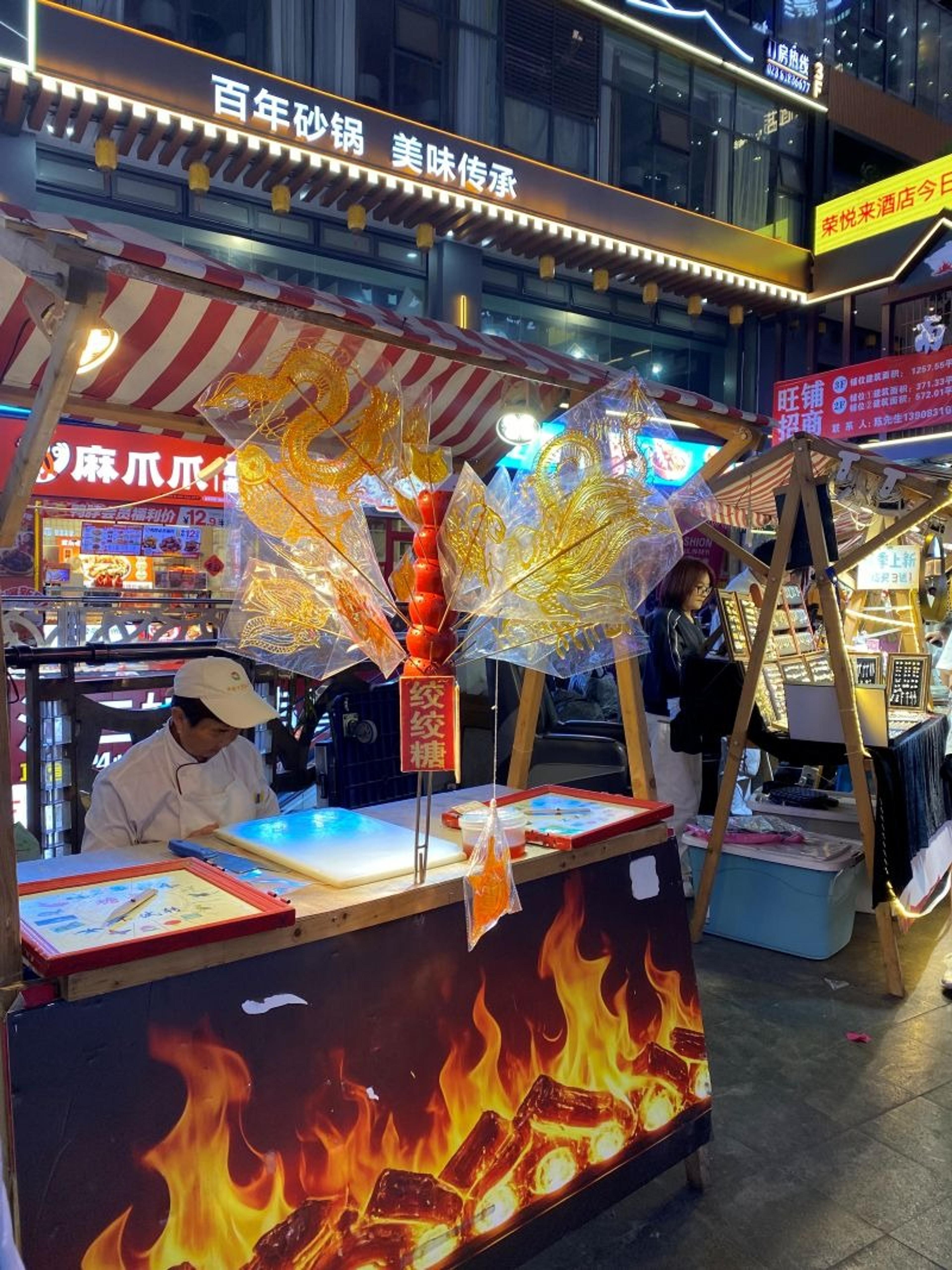 A lively street food stall is illuminated at night in a bustling market in Chengdu, China.