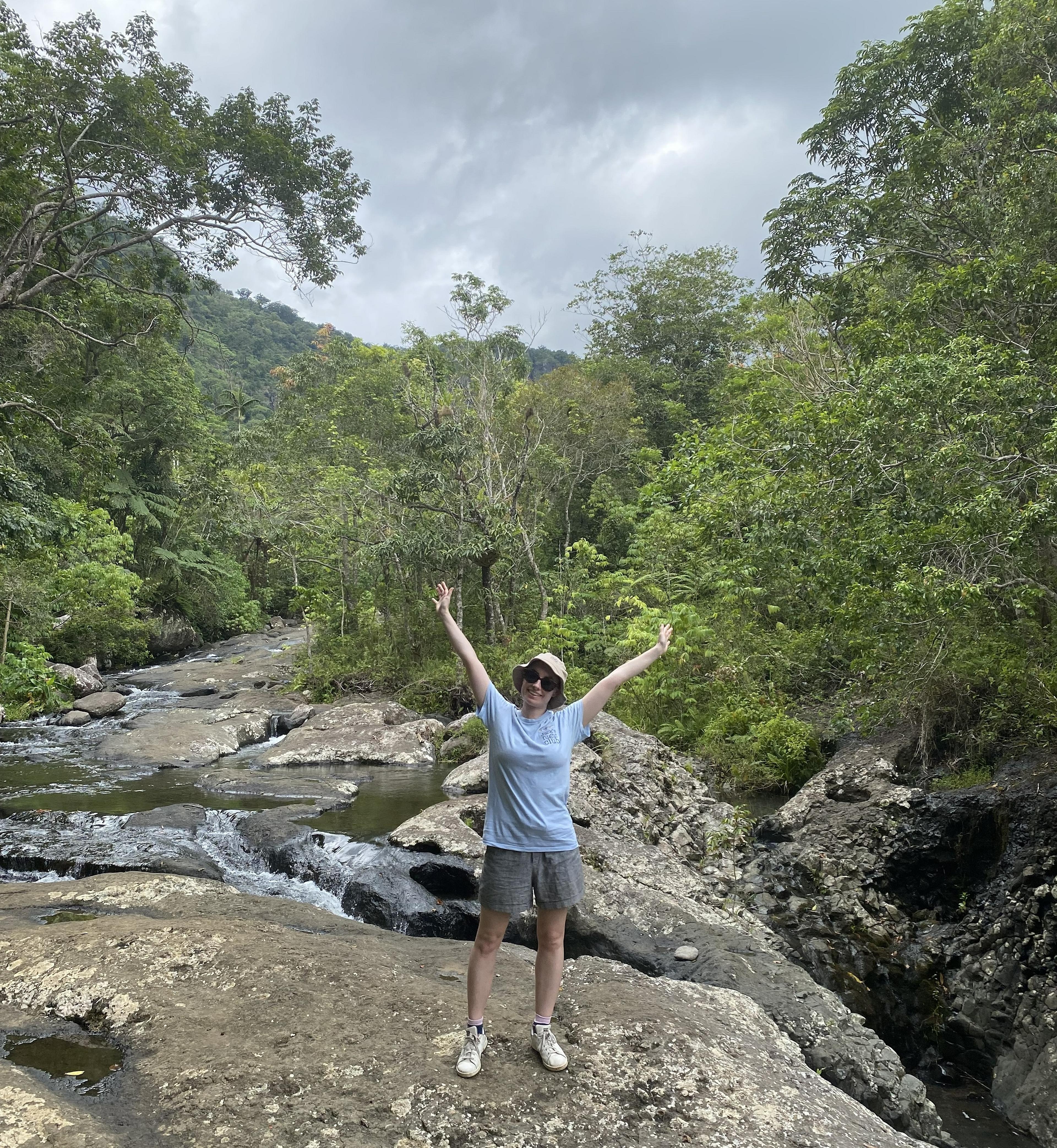 A person enjoys the lush, tropical scenery by a small river at Semenggoh Nature Reserve in Malaysia.