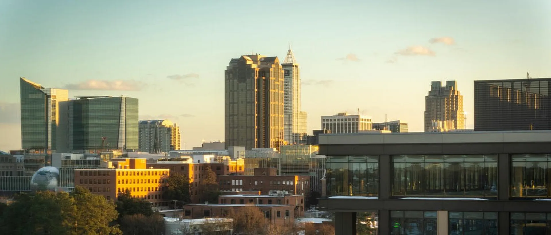 Golden-hour light illuminates the modern skyline of Raleigh, North Carolina, with its distinctive skyscrapers and urban landscape.