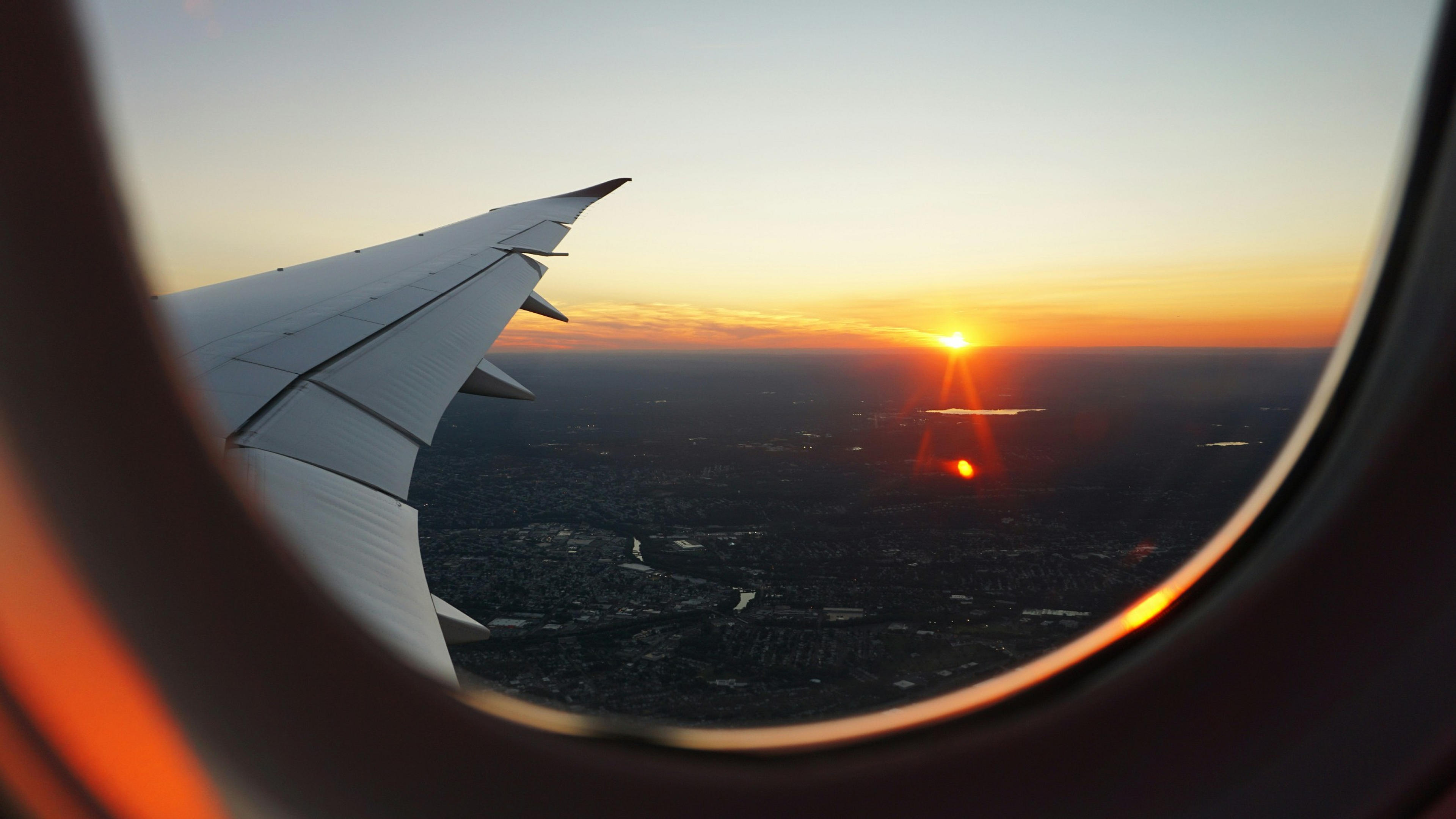 A view from an airplane window capturing a sunset over a landscape.