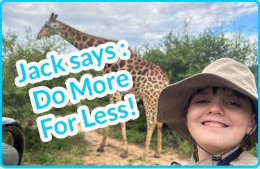 A smiling child wearing a safari hat poses in front of a giraffe
