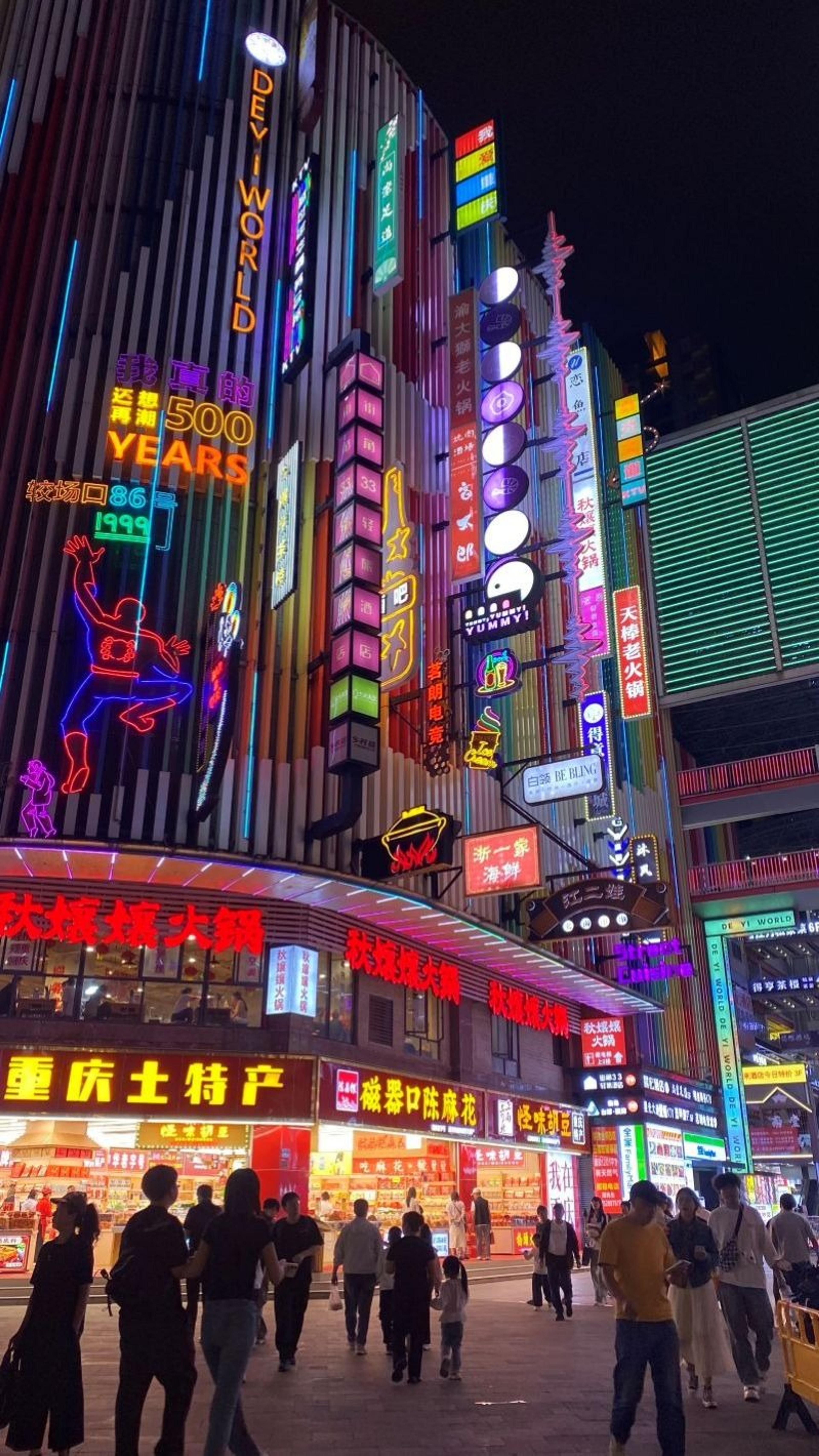 A vibrant and bustling night scene in Shanghai, China, featuring brightly lit neon signs and busy streets filled with people.