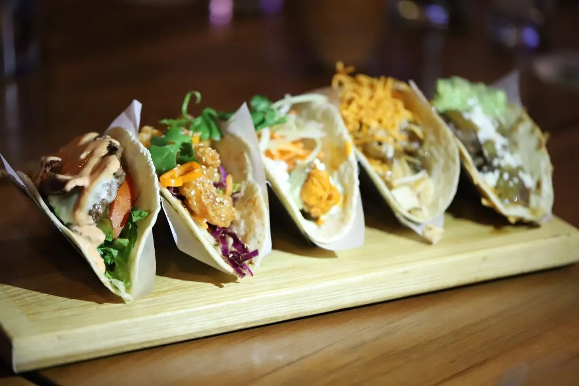 A selection of tacos artfully arranged on a wooden cutting board