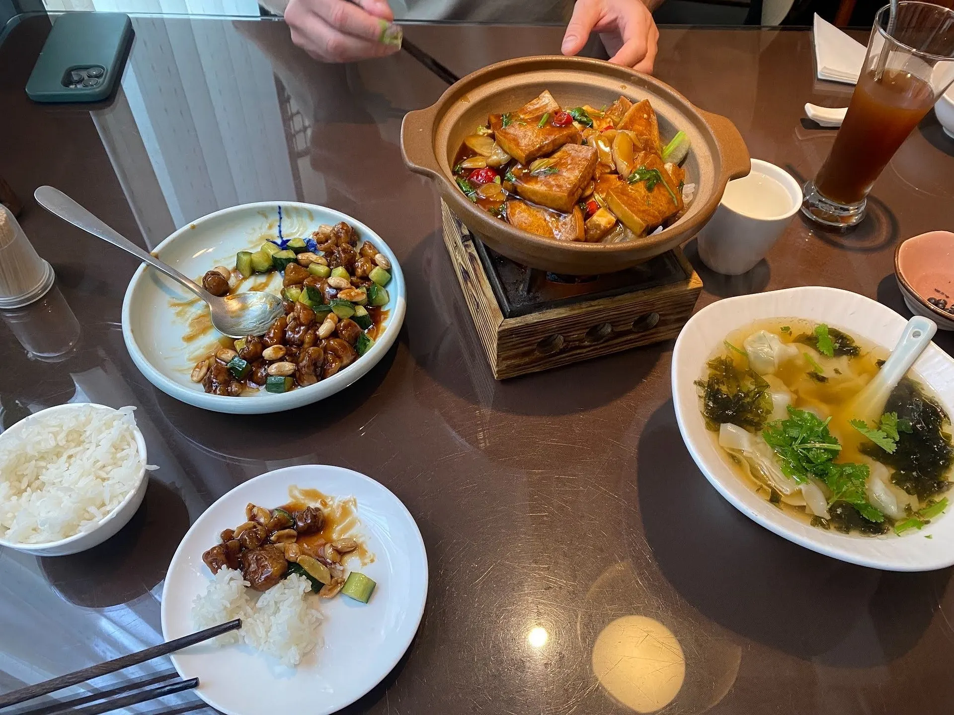 A traditional Chinese meal with various dishes is served on a glossy table, possibly in a restaurant setting.
