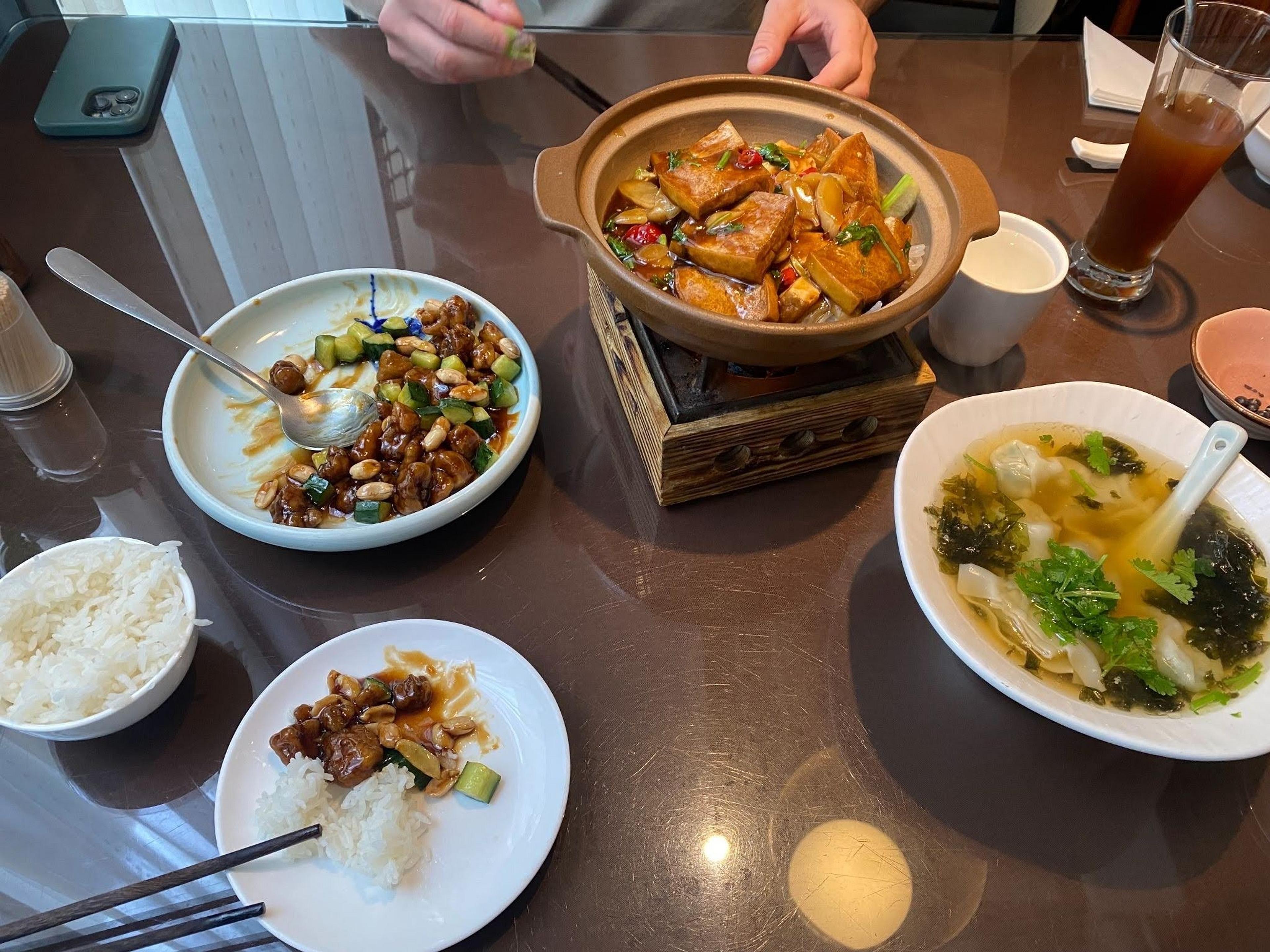 A traditional Chinese meal with various dishes is served on a glossy table, possibly in a restaurant setting.