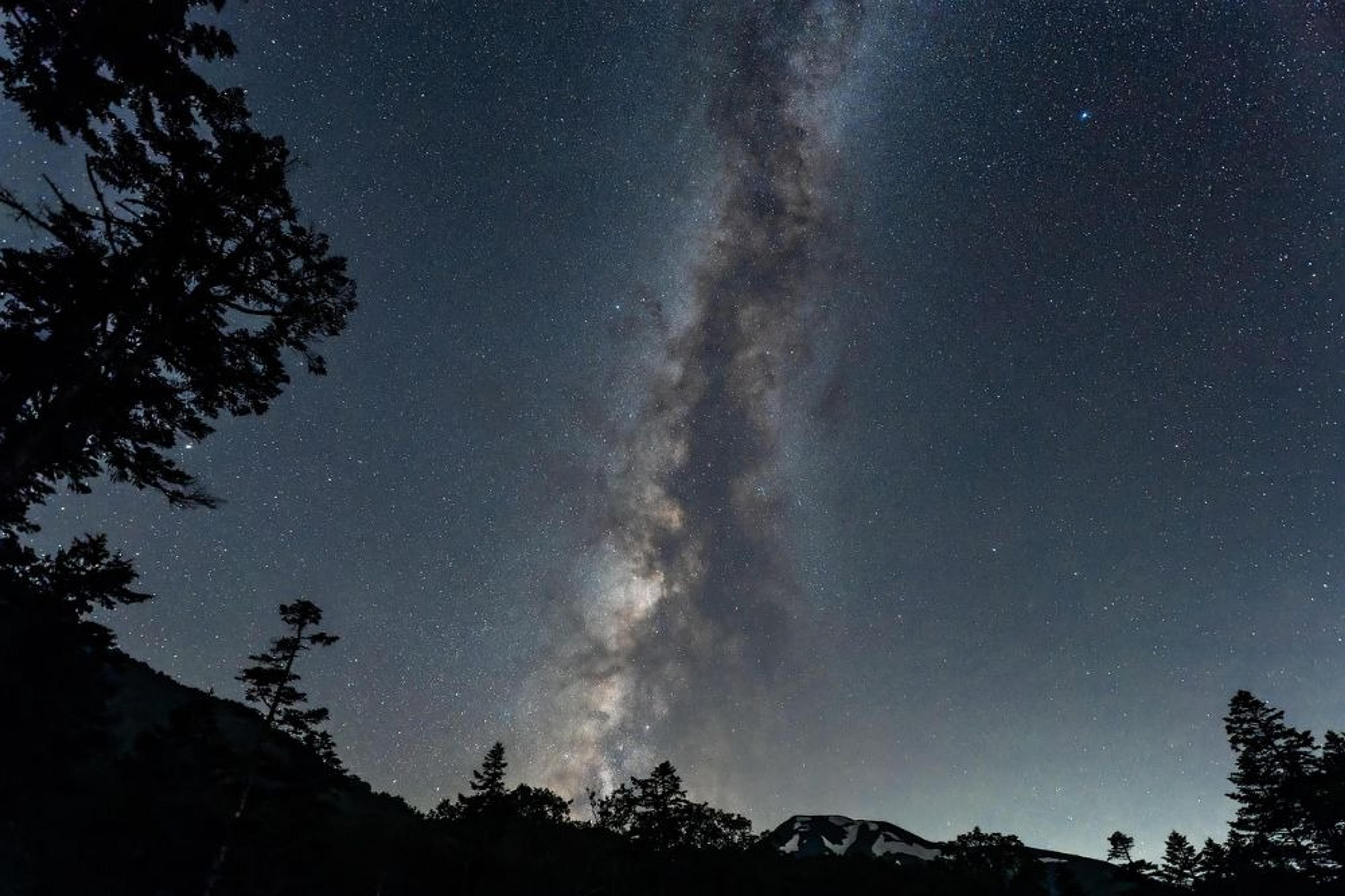 A breathtaking view of the Milky Way stretches across the night sky above the silhouetted peaks of Mt. Yotei, Japan.