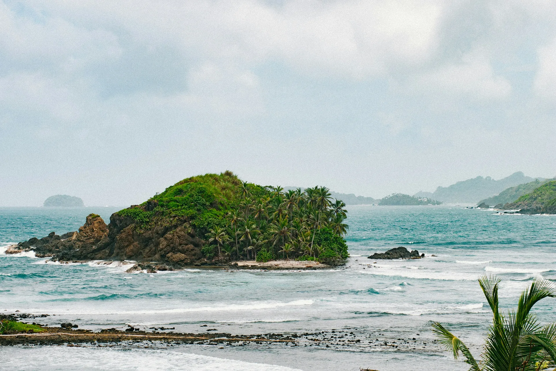 A lush, palm-covered island emerges from the waters