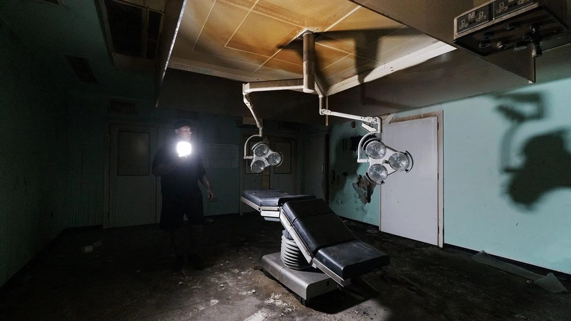 Simon, an urban explorer standing in a dimly lit abandoned morgue