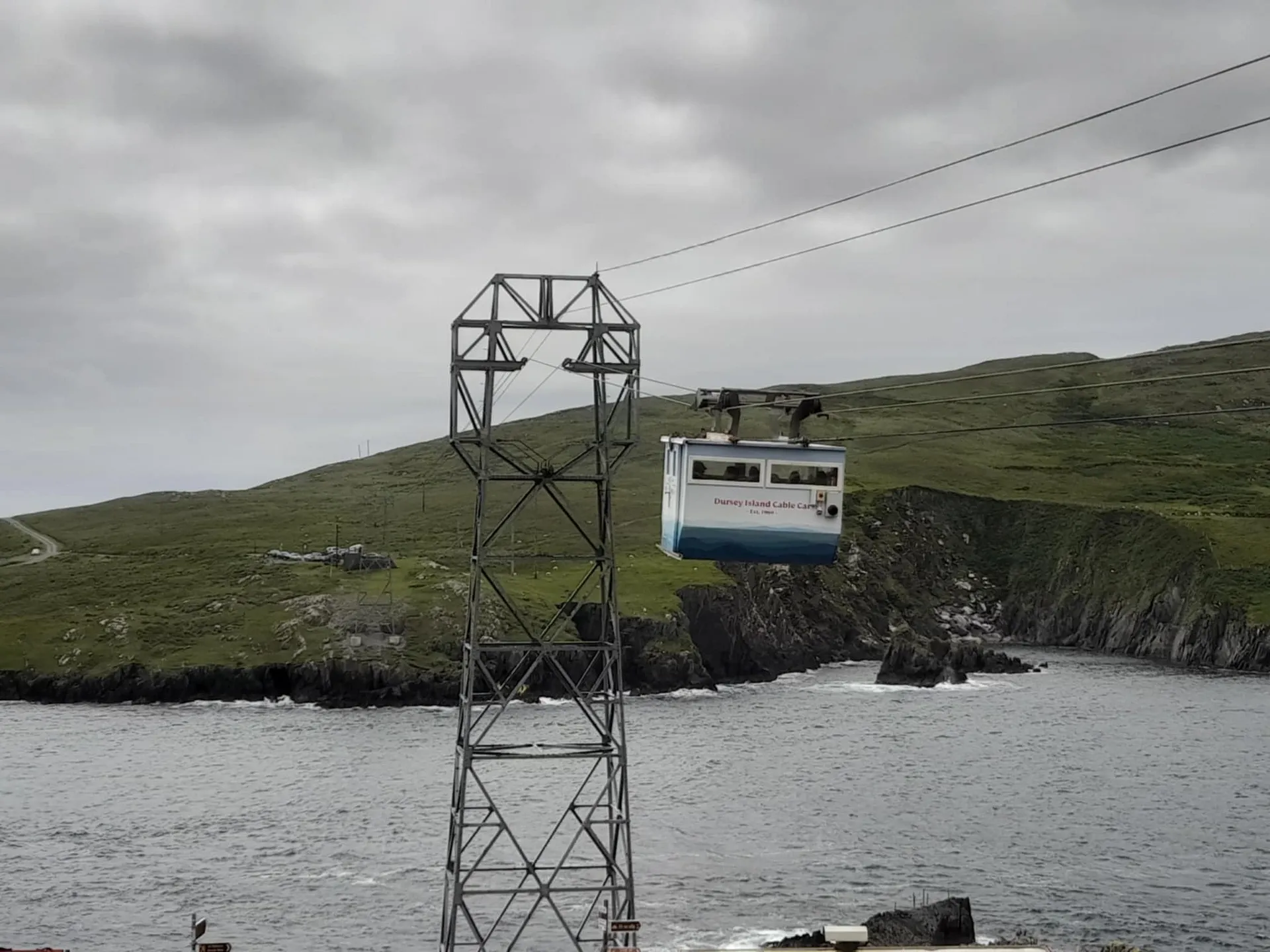 A cable car traverses over rugged cliffs and the sea at Dursey Island in Ireland.