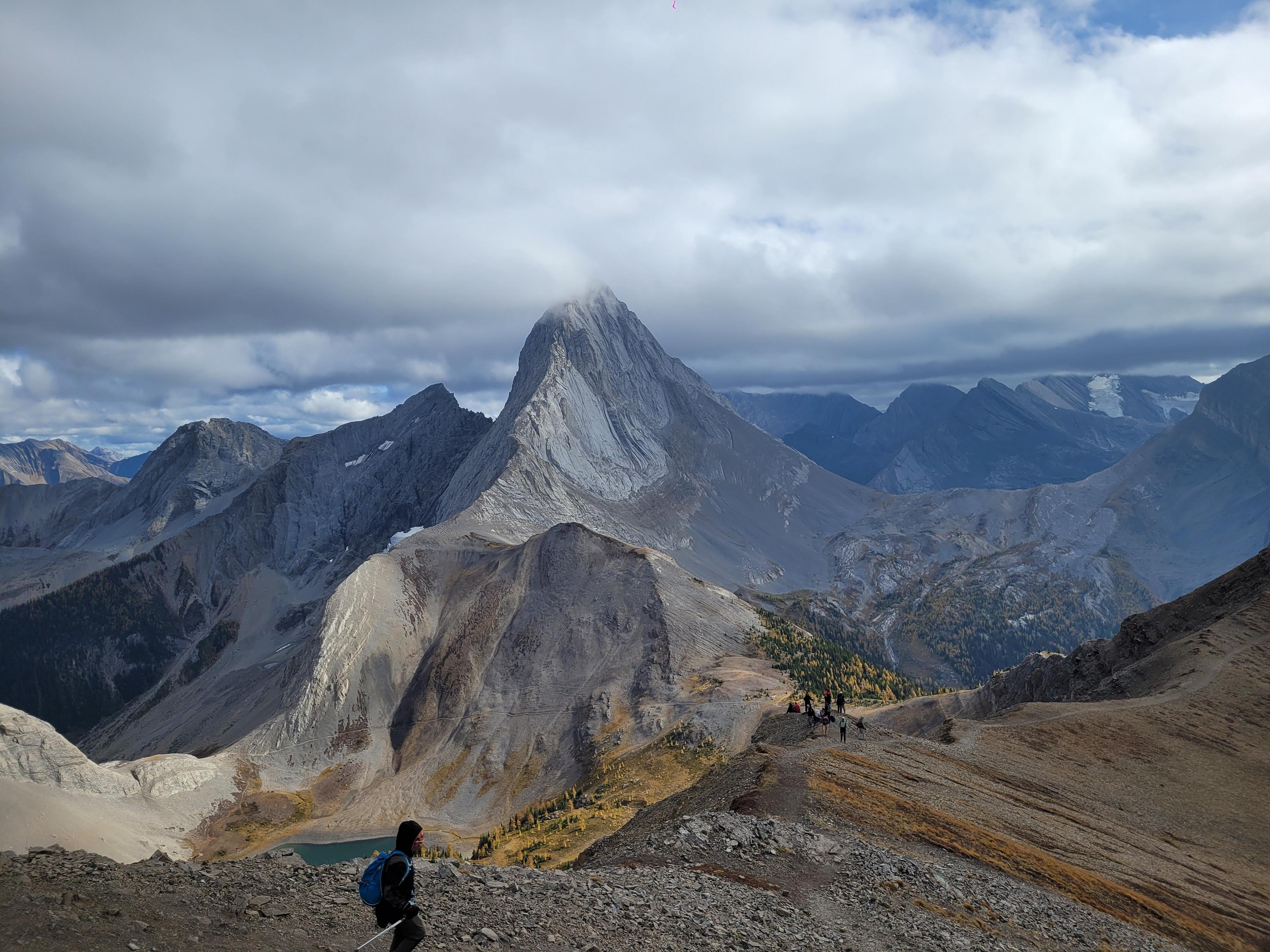 A hiker walks along a ridge in front of the towering peaks of The Fortress in Kananaskis Country, Alberta.