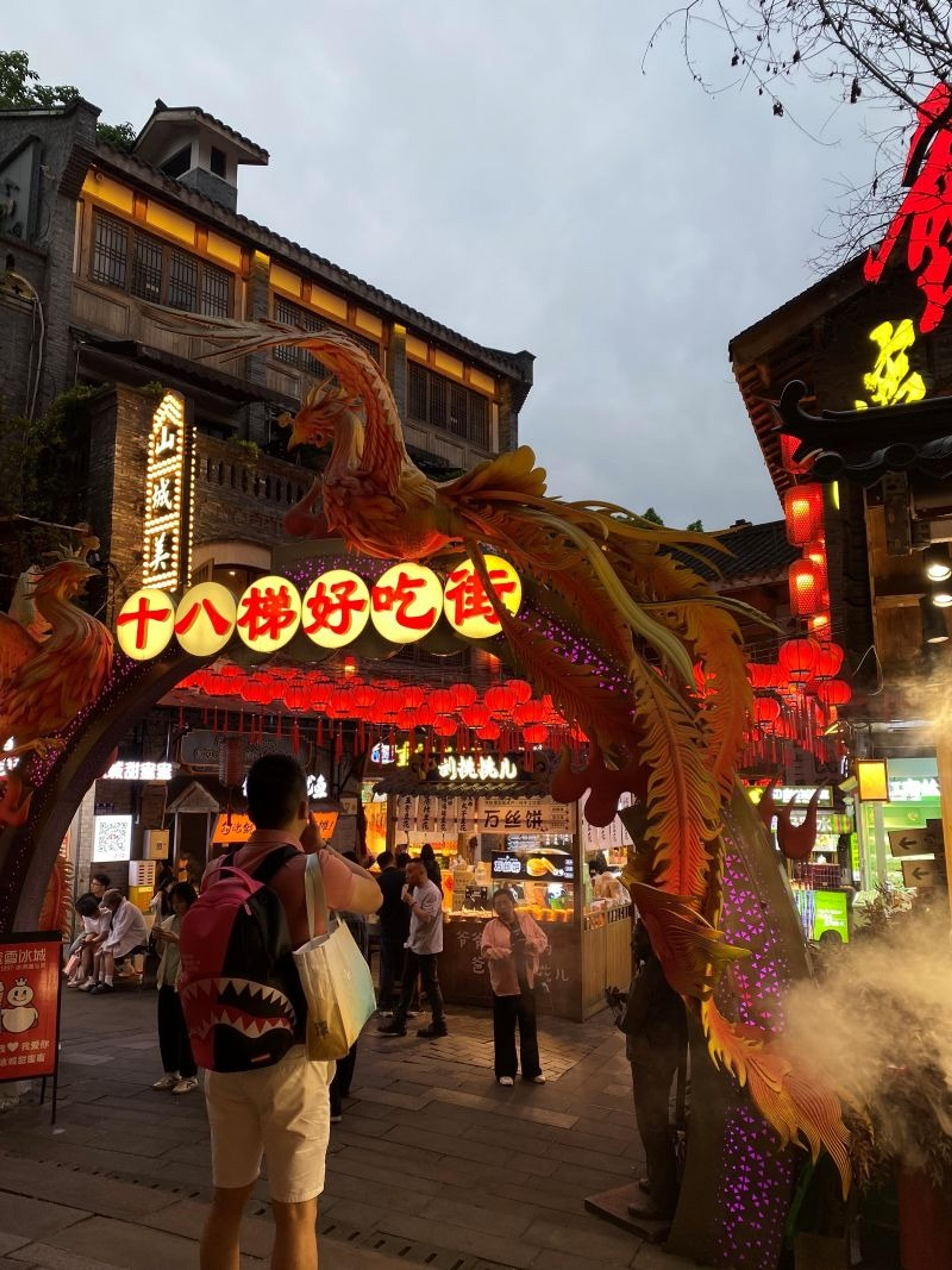 A bustling, lantern-lit street in Chongqing, China, features vibrant decorations and food stalls.