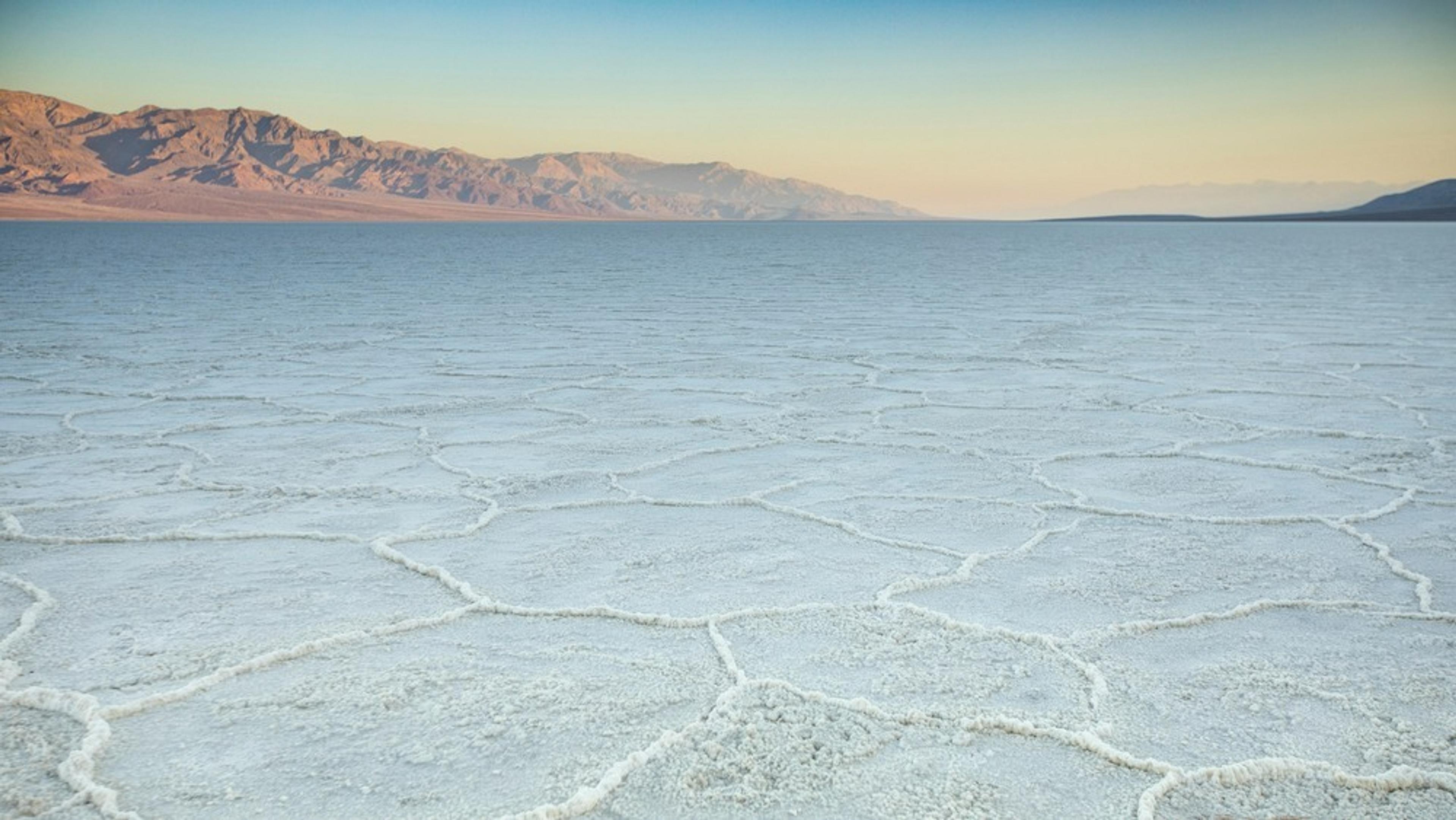 Expansive salt flats stretch across Badwater Basin in Death Valley, California, with distant mountains skirting the horizon.