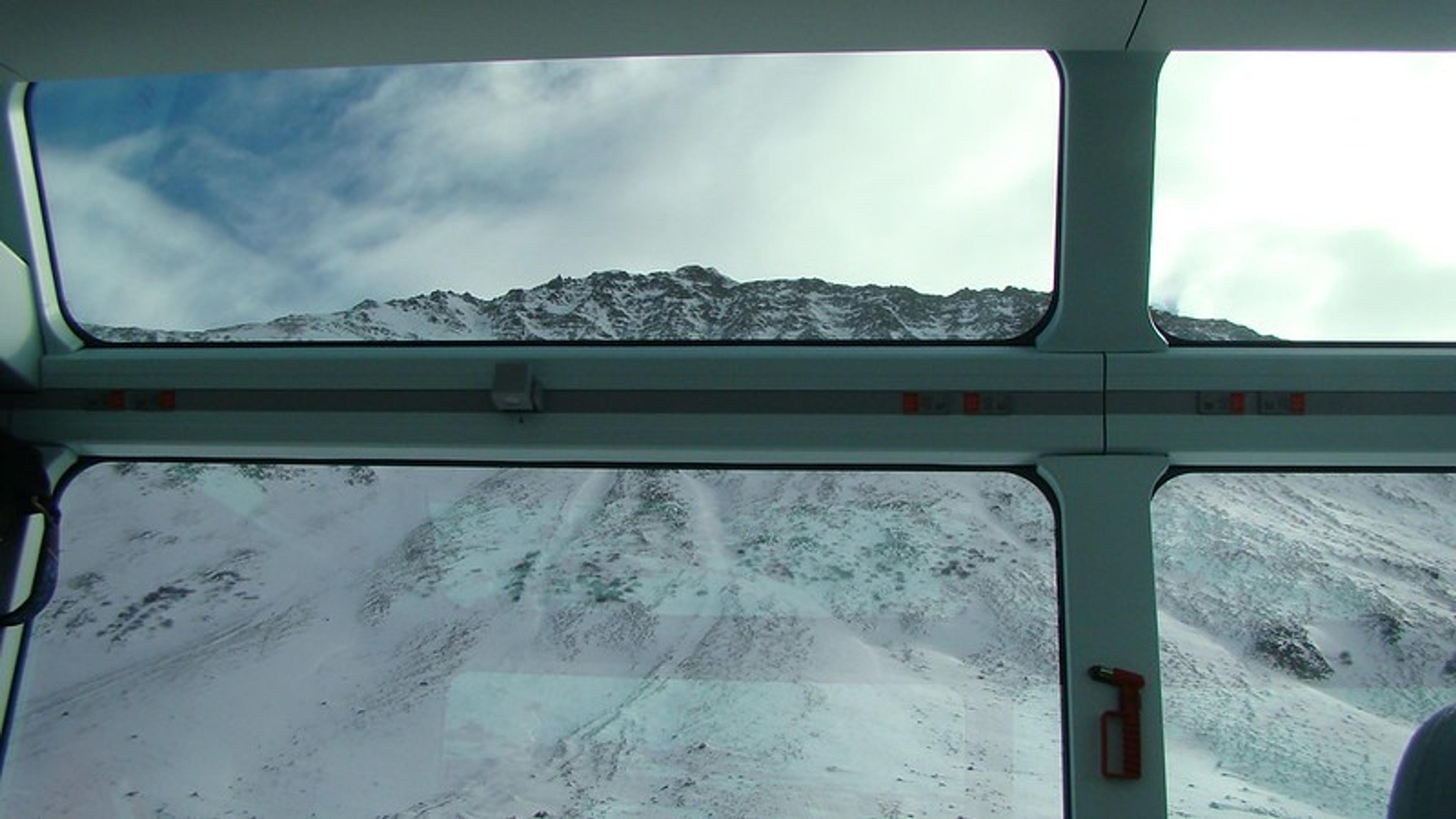 A snowy mountain peak viewed through the panoramic windows of the Bernina Express in the Swiss Alps.