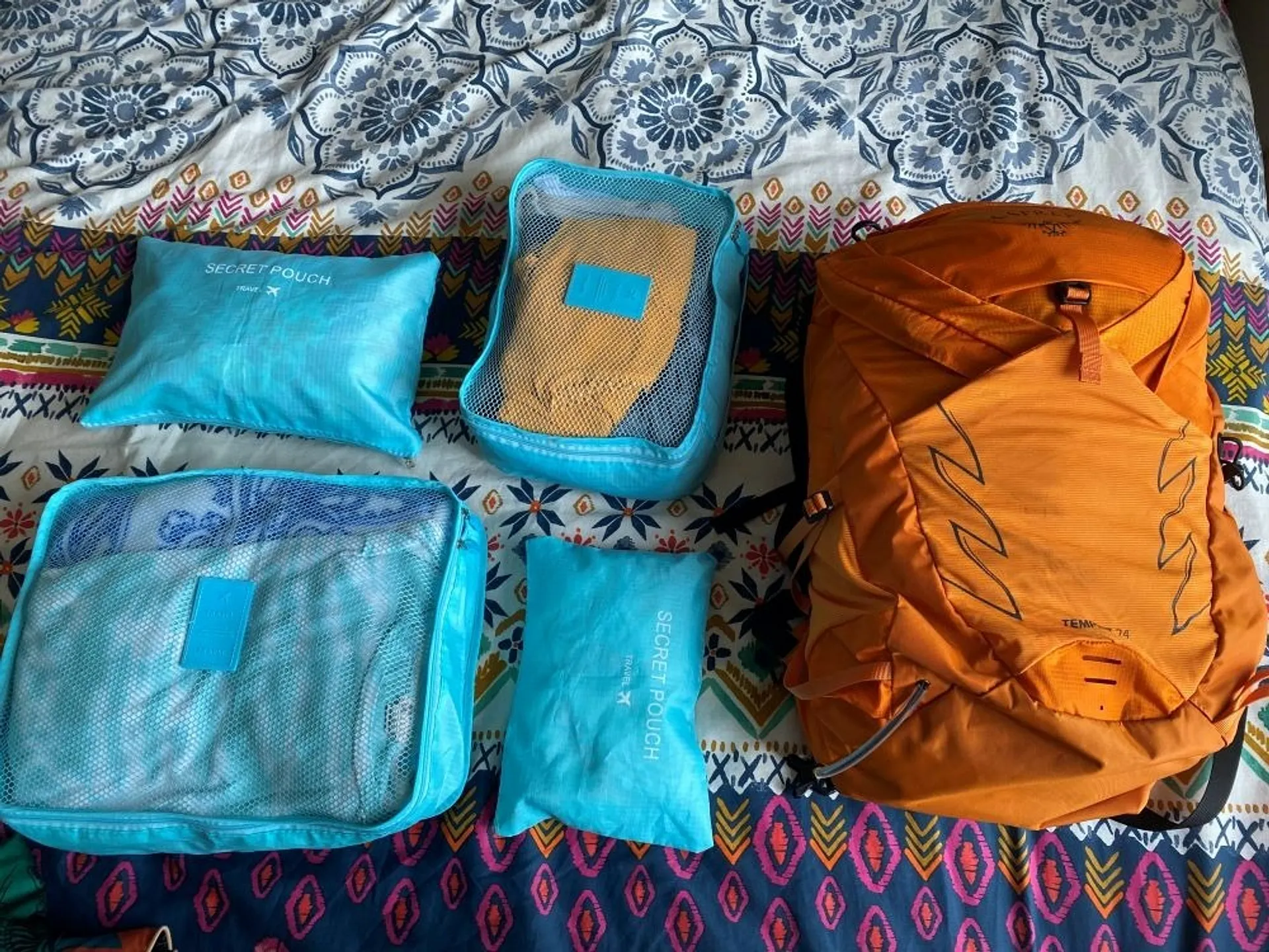 Blue packing cubes and an orange backpack