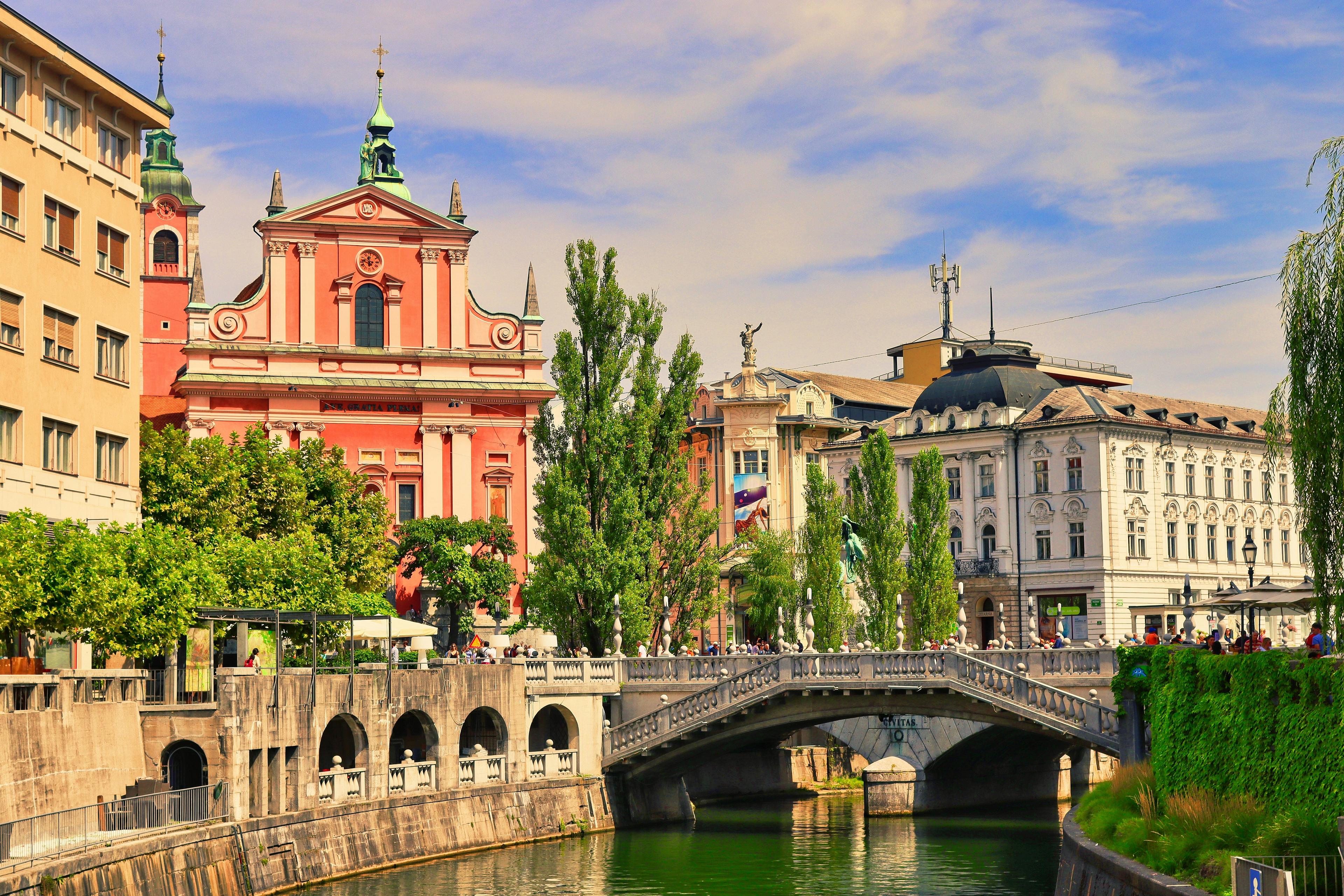 A picturesque view of the Triple Bridge and the Franciscan Church of the Annunciation along the Ljubljanica River in Ljubljana, Slovenia.