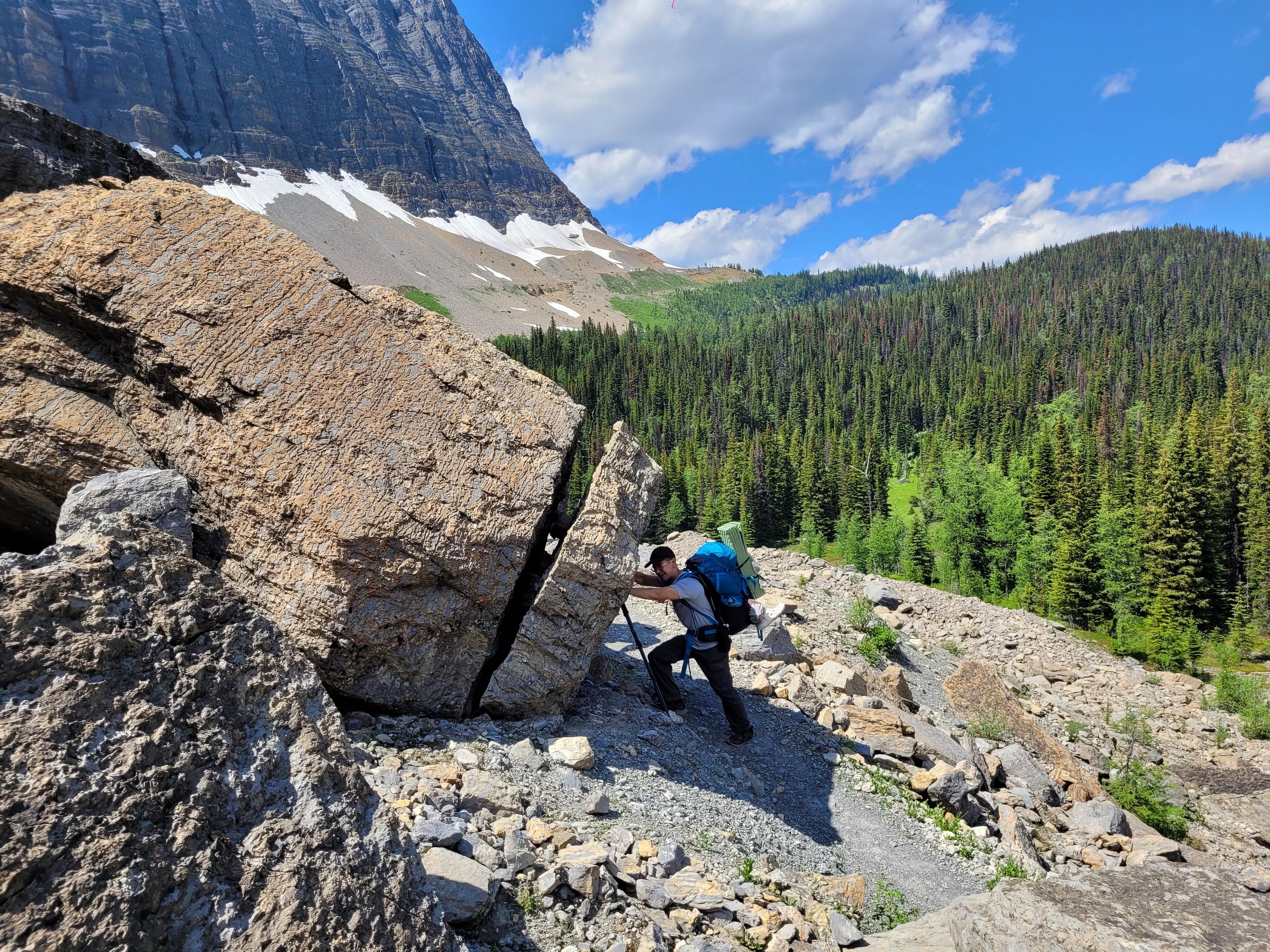 A hiker navigates rocky terrain in the mountainous landscape of Kootenay National Park, Canada.