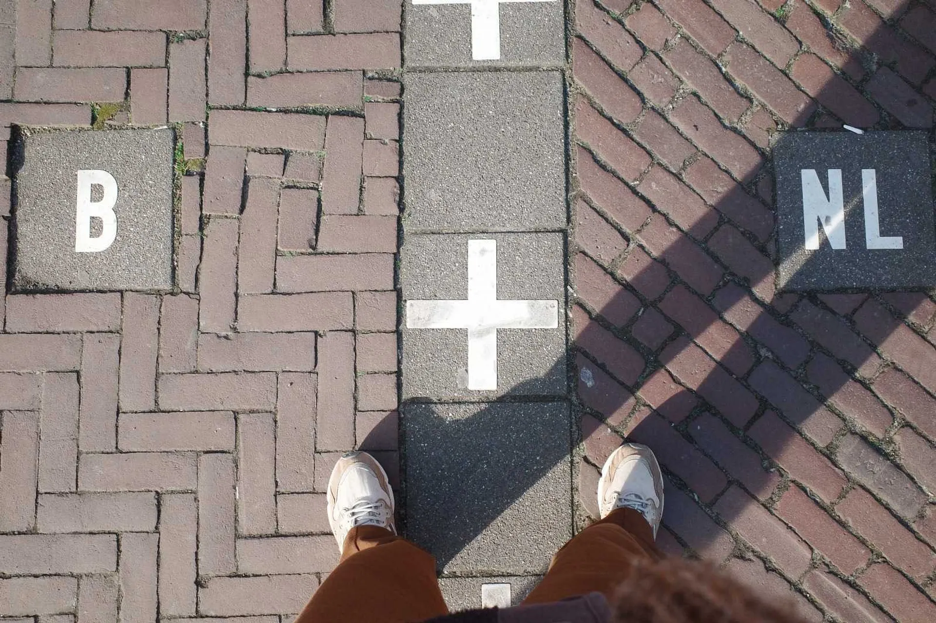 Feet standing on the international border between Belgium and the Netherlands in Baarle.