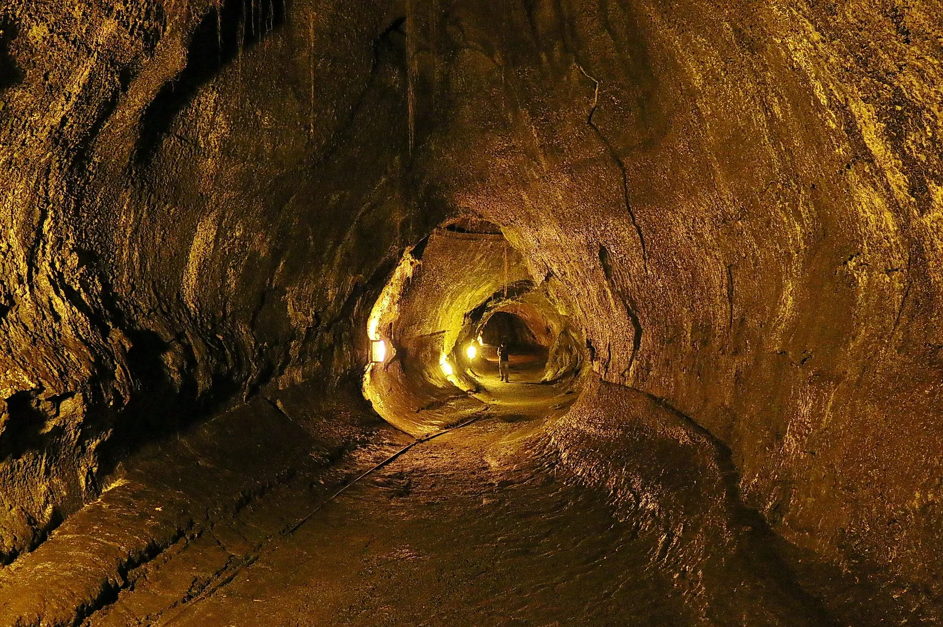 A person stands illuminated inside the Thurston Lava Tube in Hawai'i Volcanoes National Park.