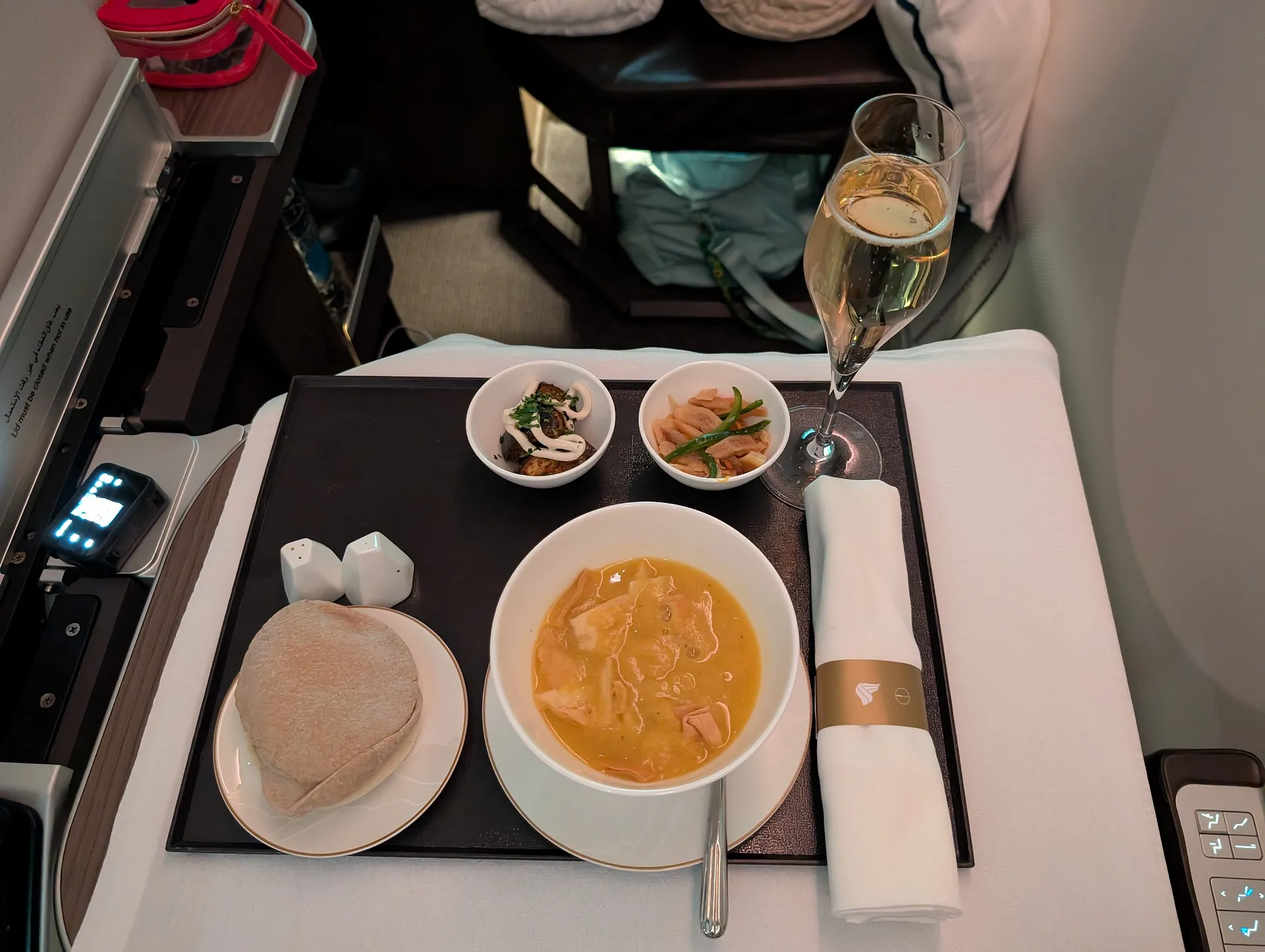 A luxurious in-flight meal is served on Oman Air, complete with champagne and an elegantly set table.