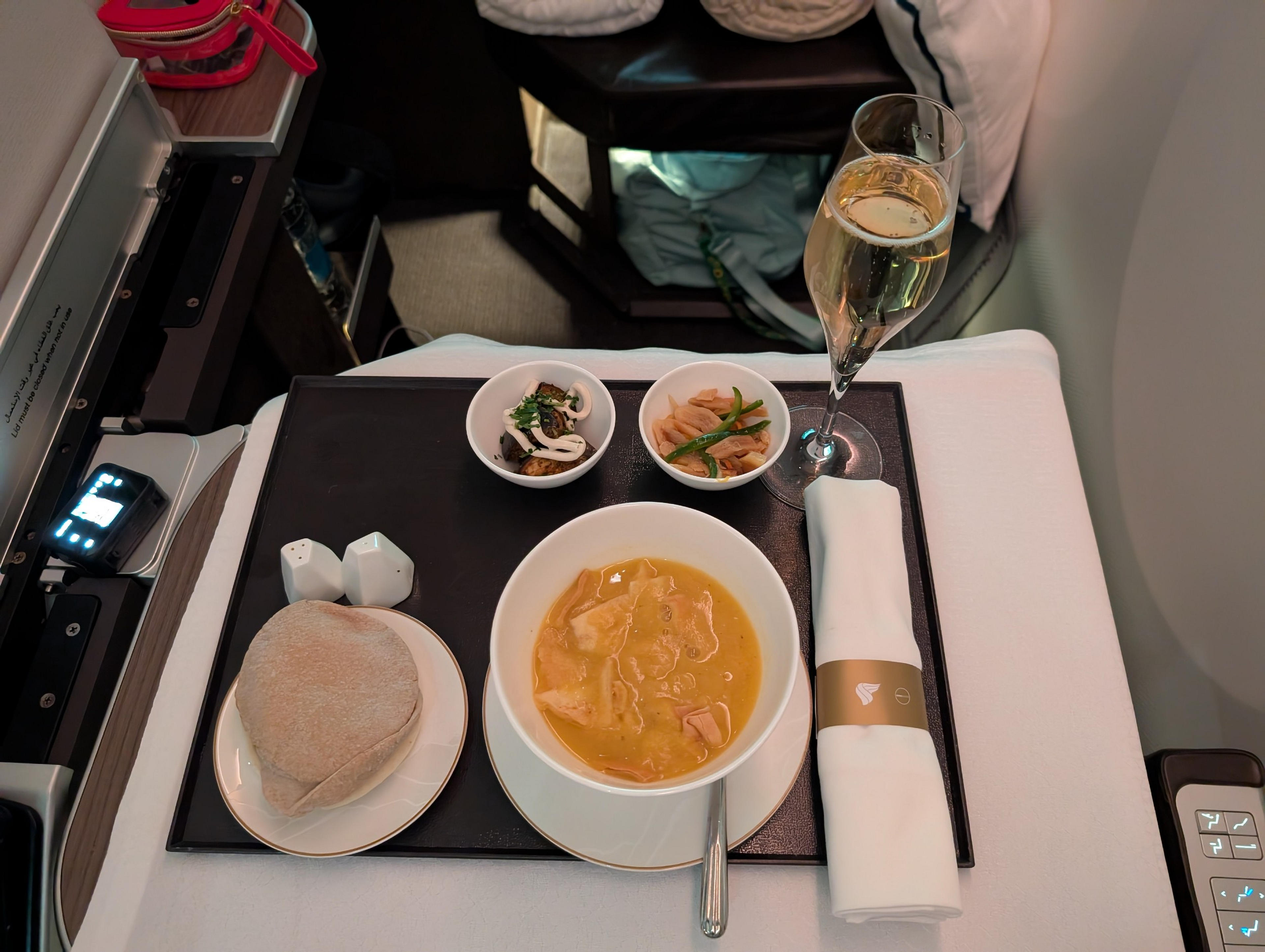 A luxurious in-flight meal is served on Oman Air, complete with champagne and an elegantly set table.