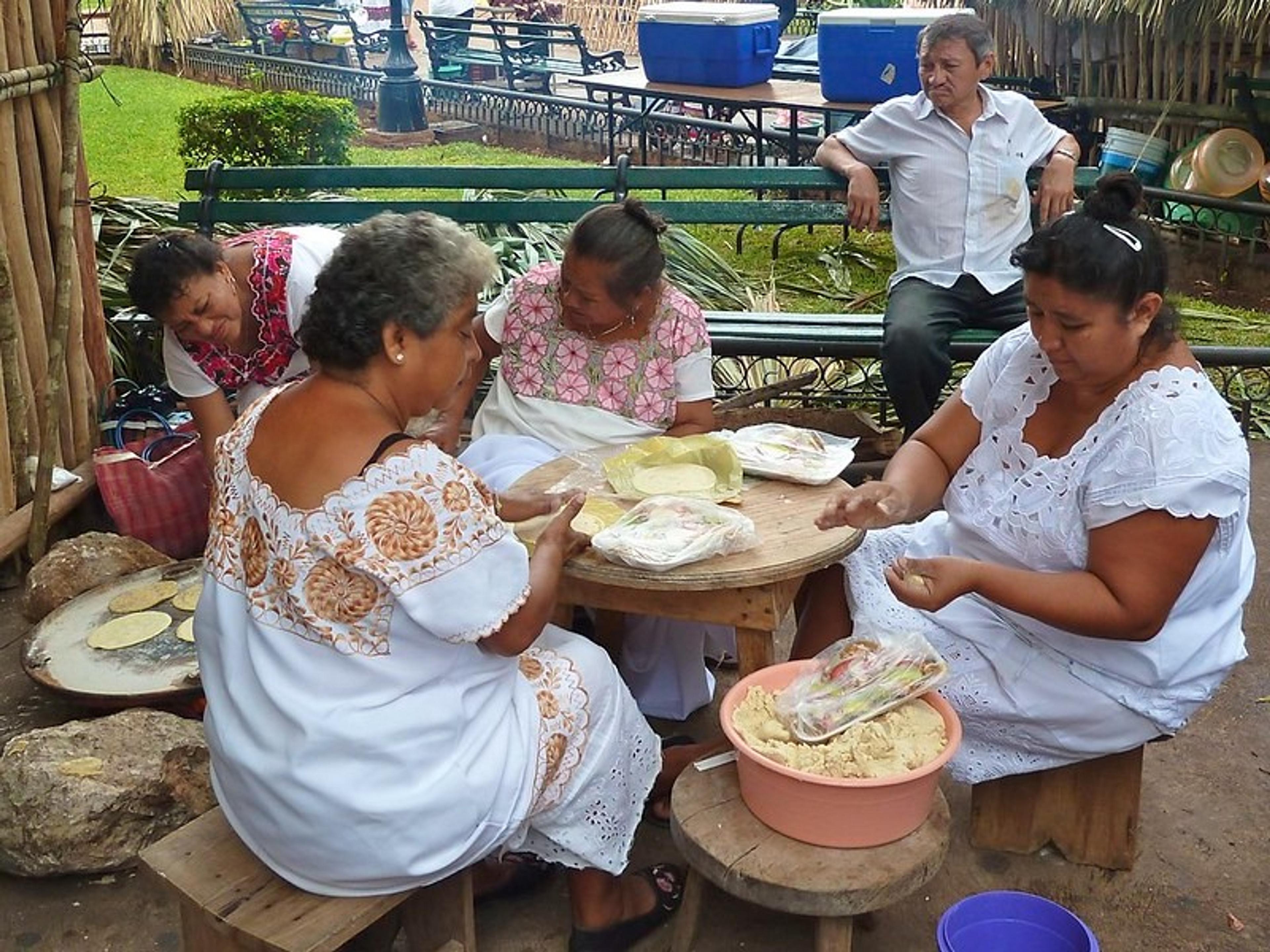 Women in traditional dresses make tortillas at a park in Mérida, Mexico.