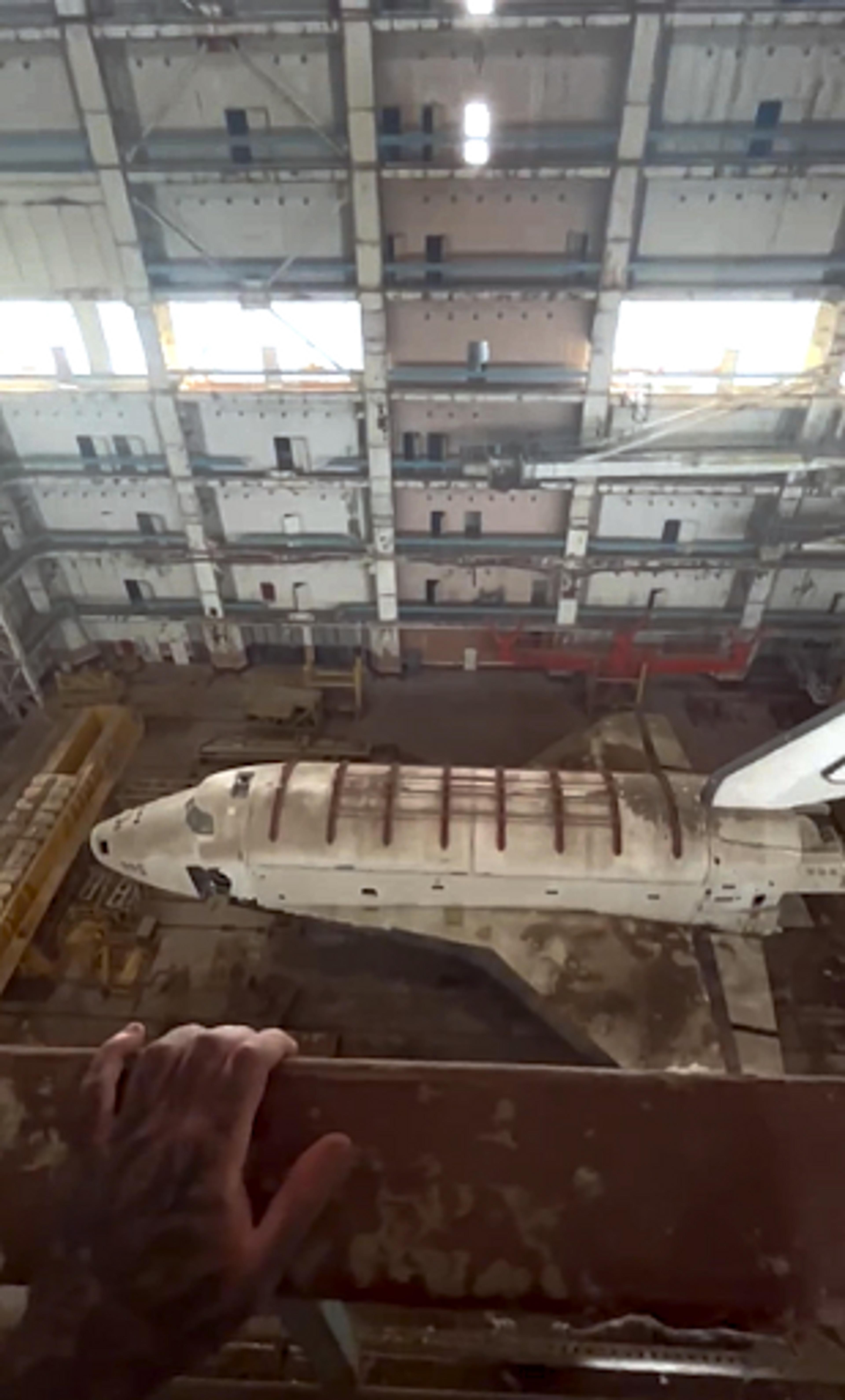 Simon's hand on a railing, looking down at the Soviet space shuttles in Baikonur