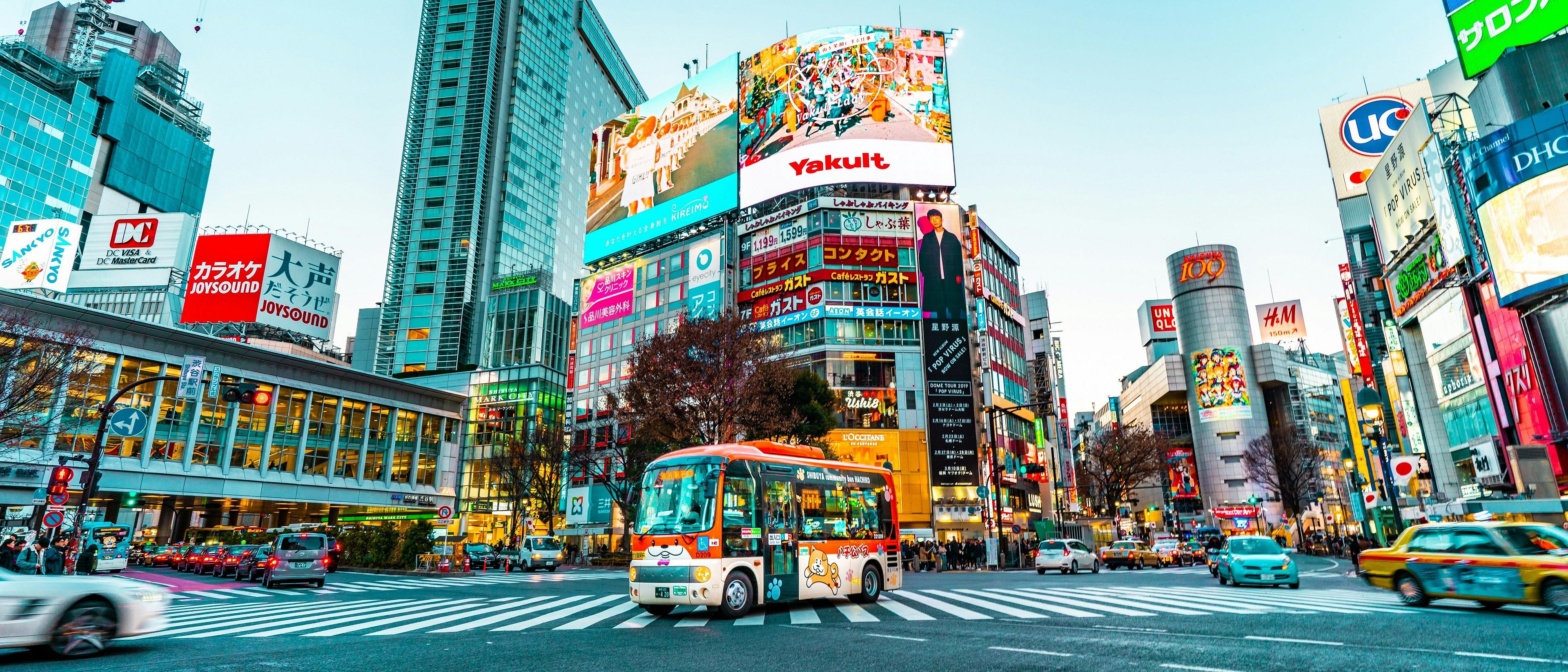 Vibrantly illuminated with colorful advertisements and bustling with vehicles, Shibuya Crossing in Tokyo captures the lively essence of urban life.
