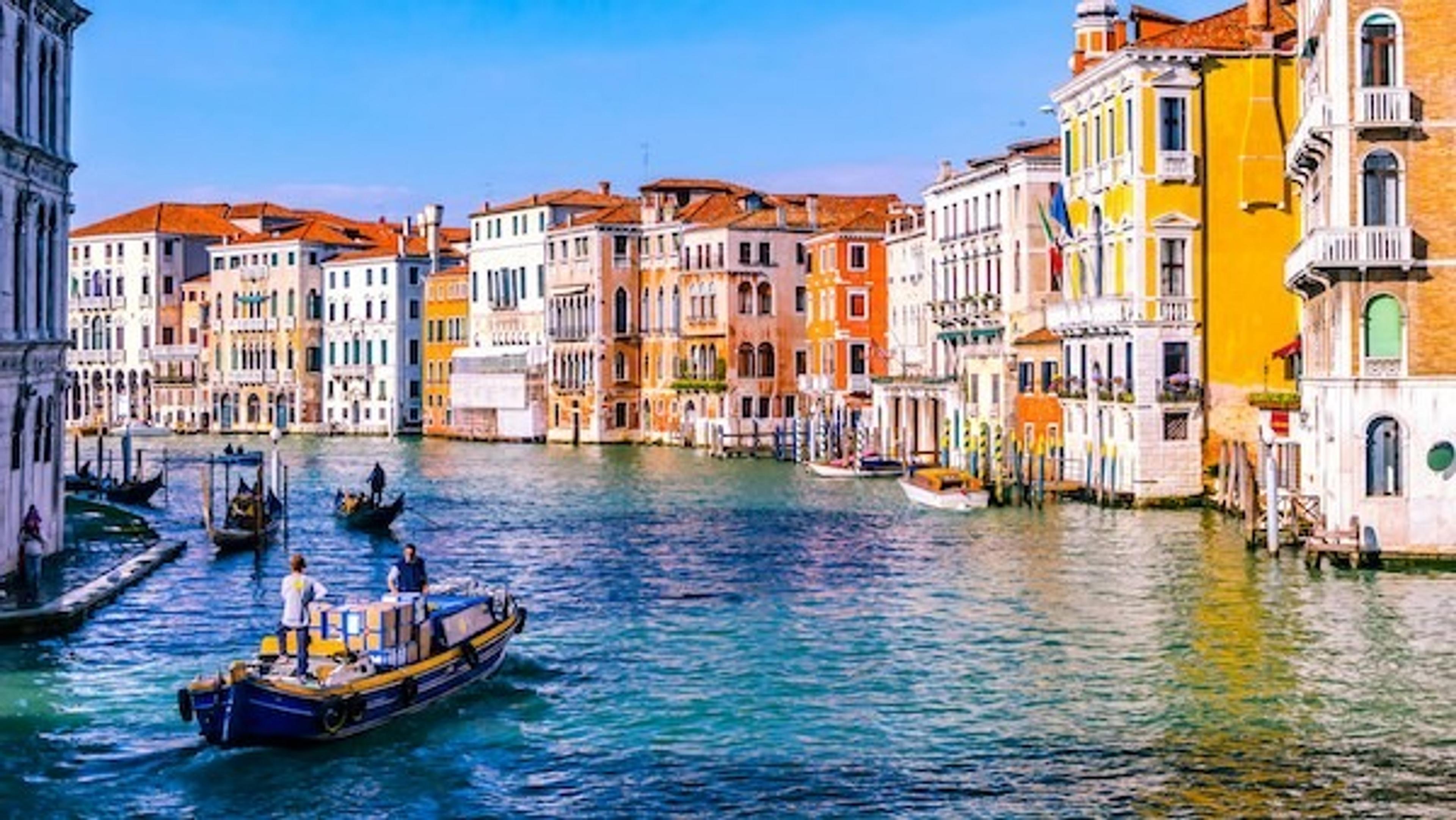 A vibrant canal bustling with boats lined by colorful historic buildings in Venice, Italy.