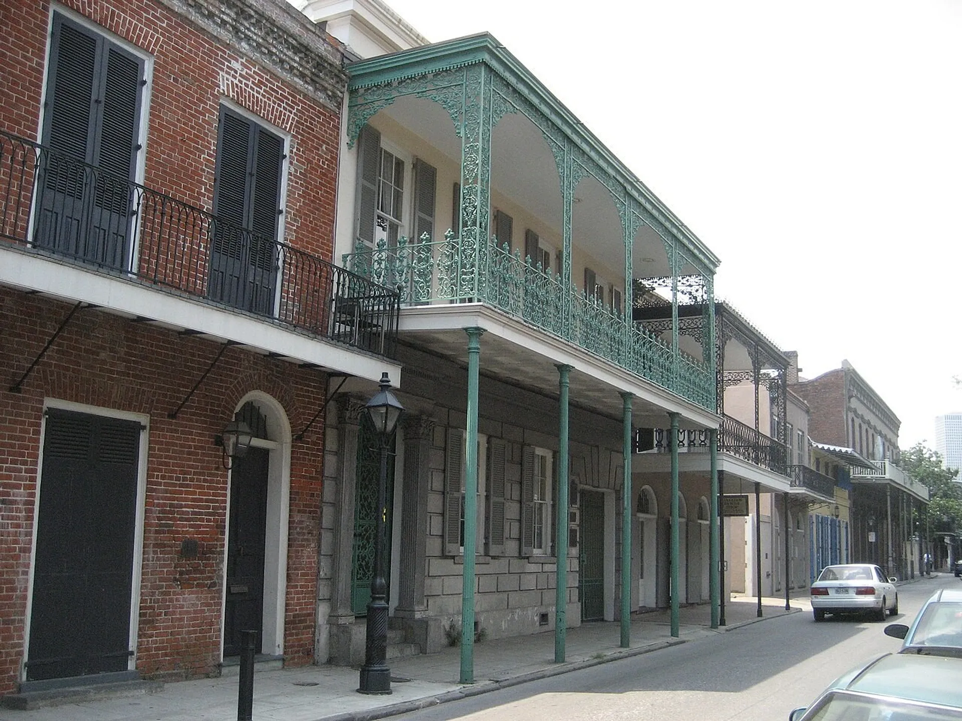 Historic buildings with wrought-iron balconies line a street in the French Quarter of New Orleans.
