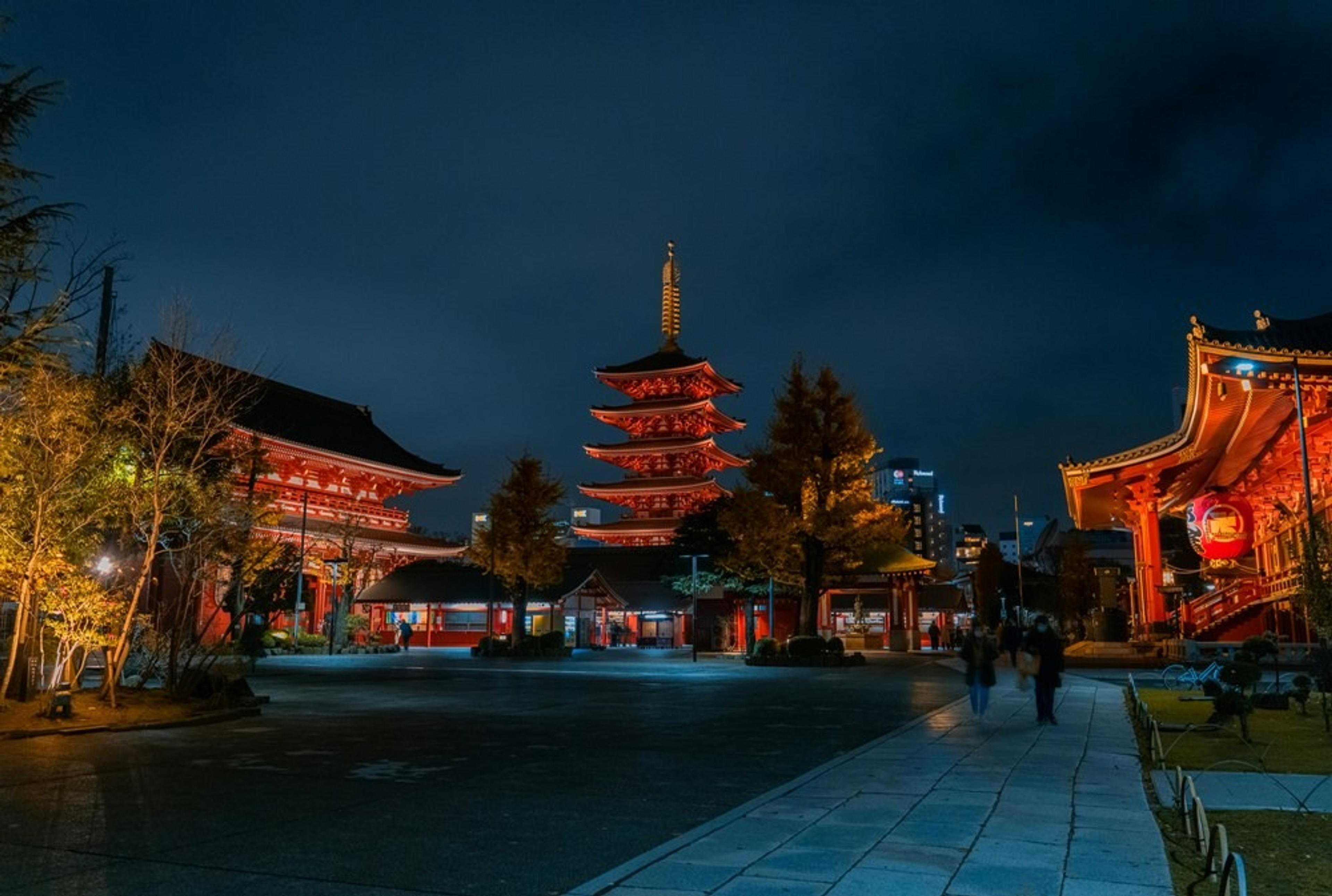 A serene evening scene at Senso-ji Temple in Tokyo, Japan, with its iconic red architecture beautifully illuminated.