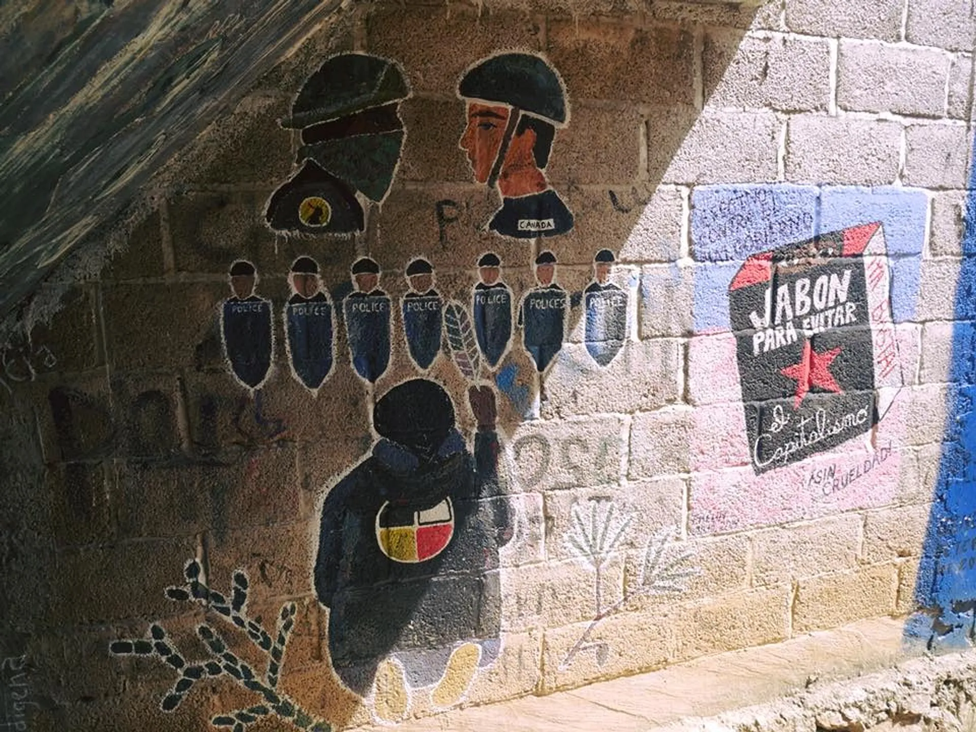A mural in San Cristóbal de las Casas, Chiapas, depicts police figures and political messages on a brick wall under a bridge.