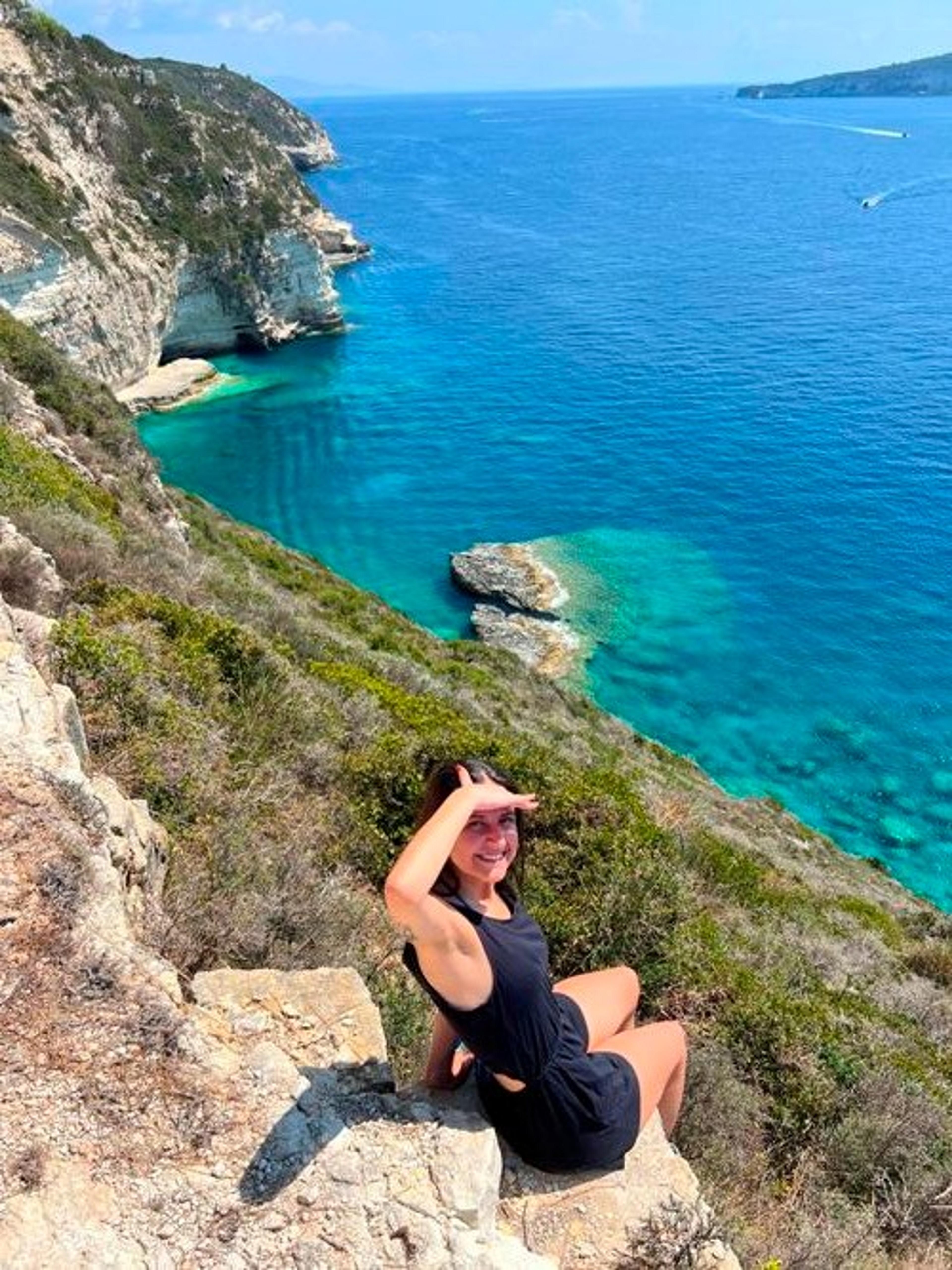 Andreia sitting by a cliff over the sea