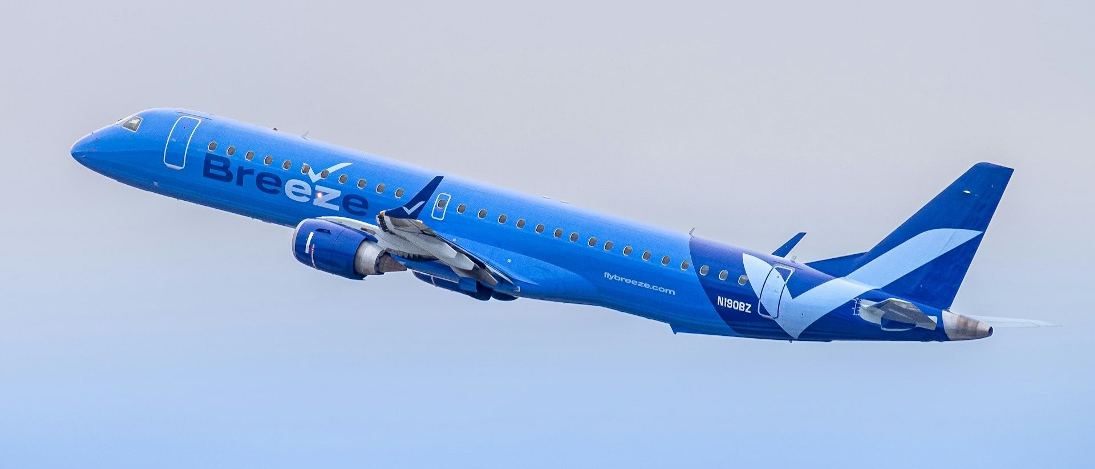 A Breeze Airways aircraft ascends against a clear sky.