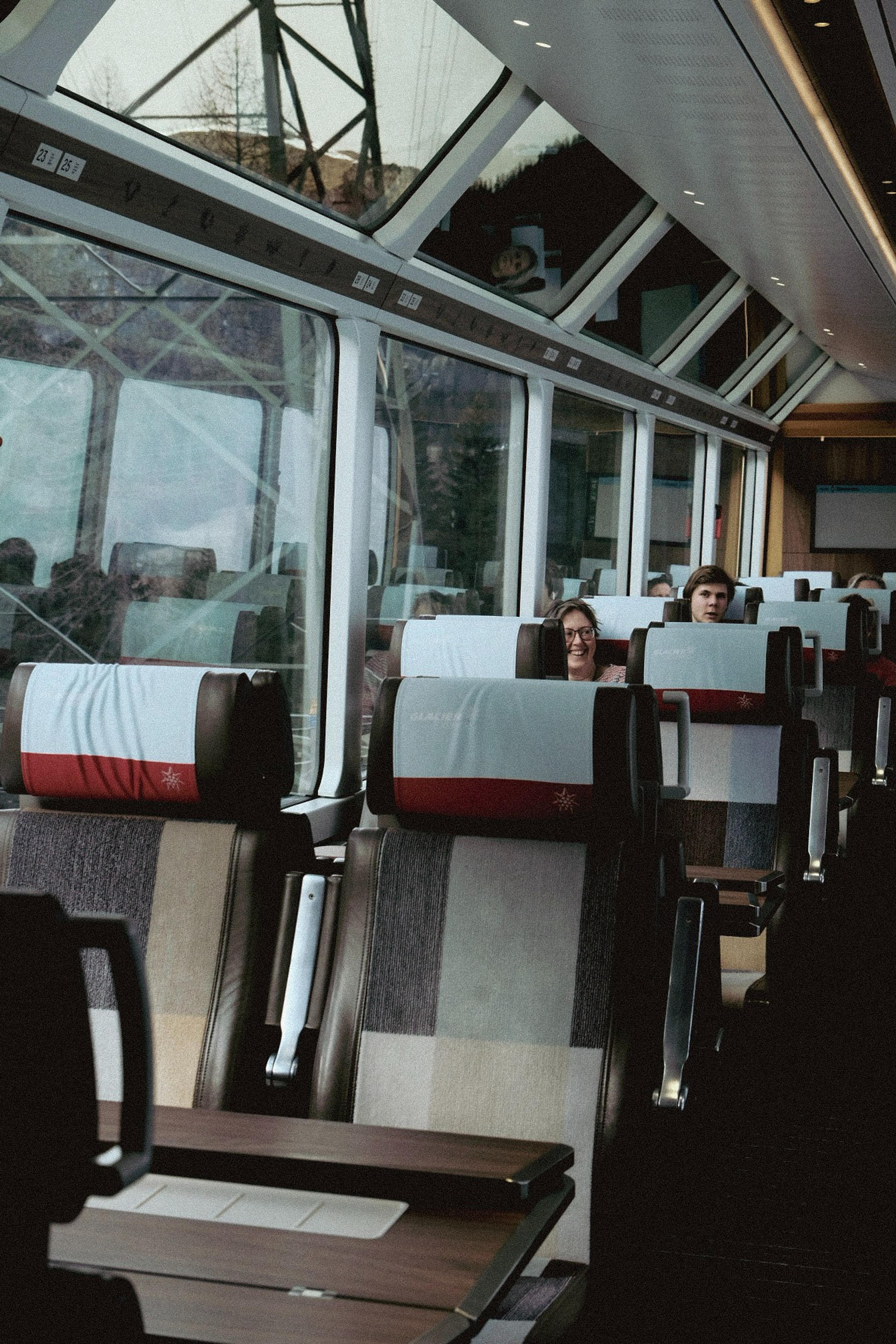 Passengers enjoy the scenic views inside a Glacier Express train in Switzerland, characterized by its large panoramic windows.