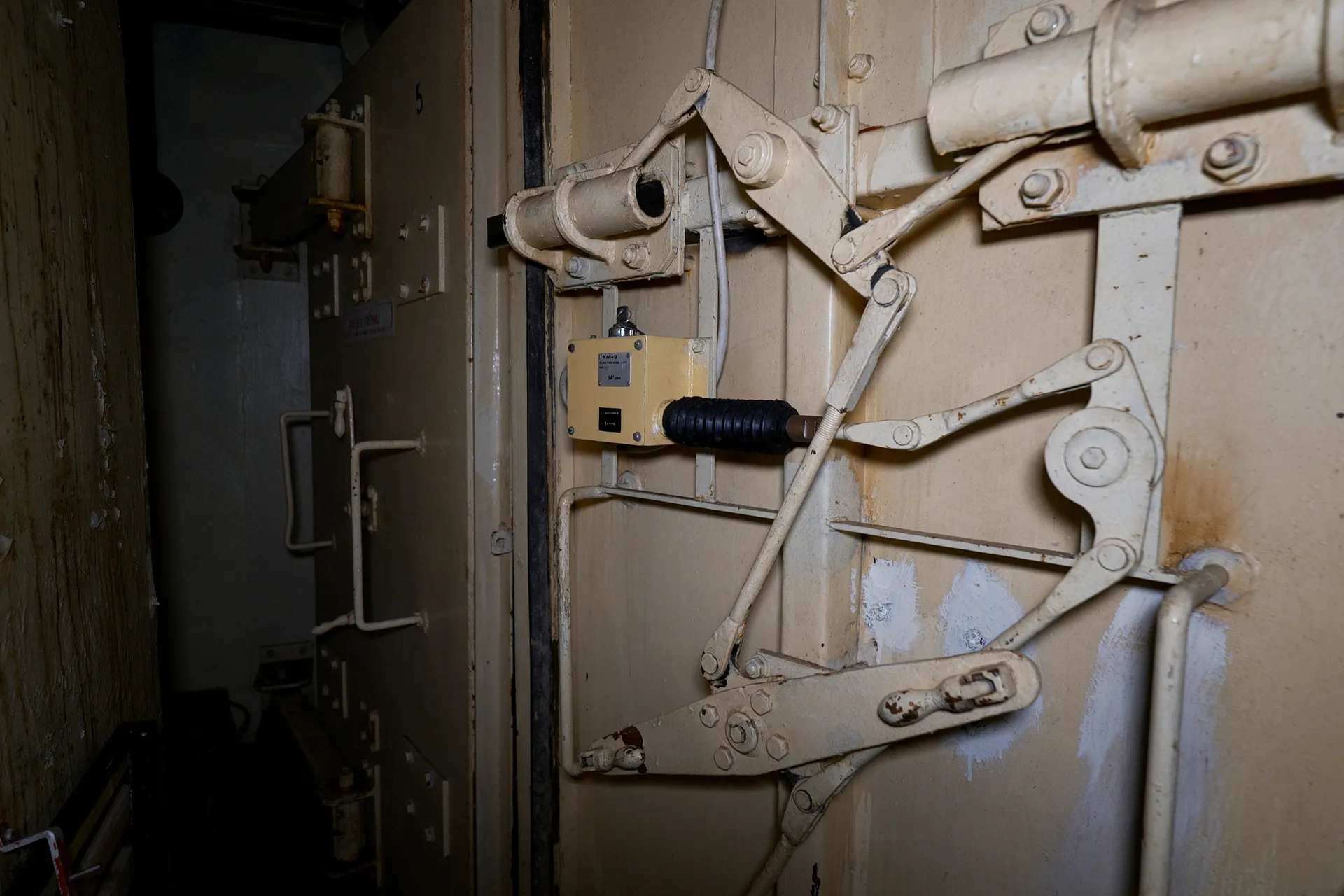 A rusty steel door revealing a labryinth of rooms within the bunker