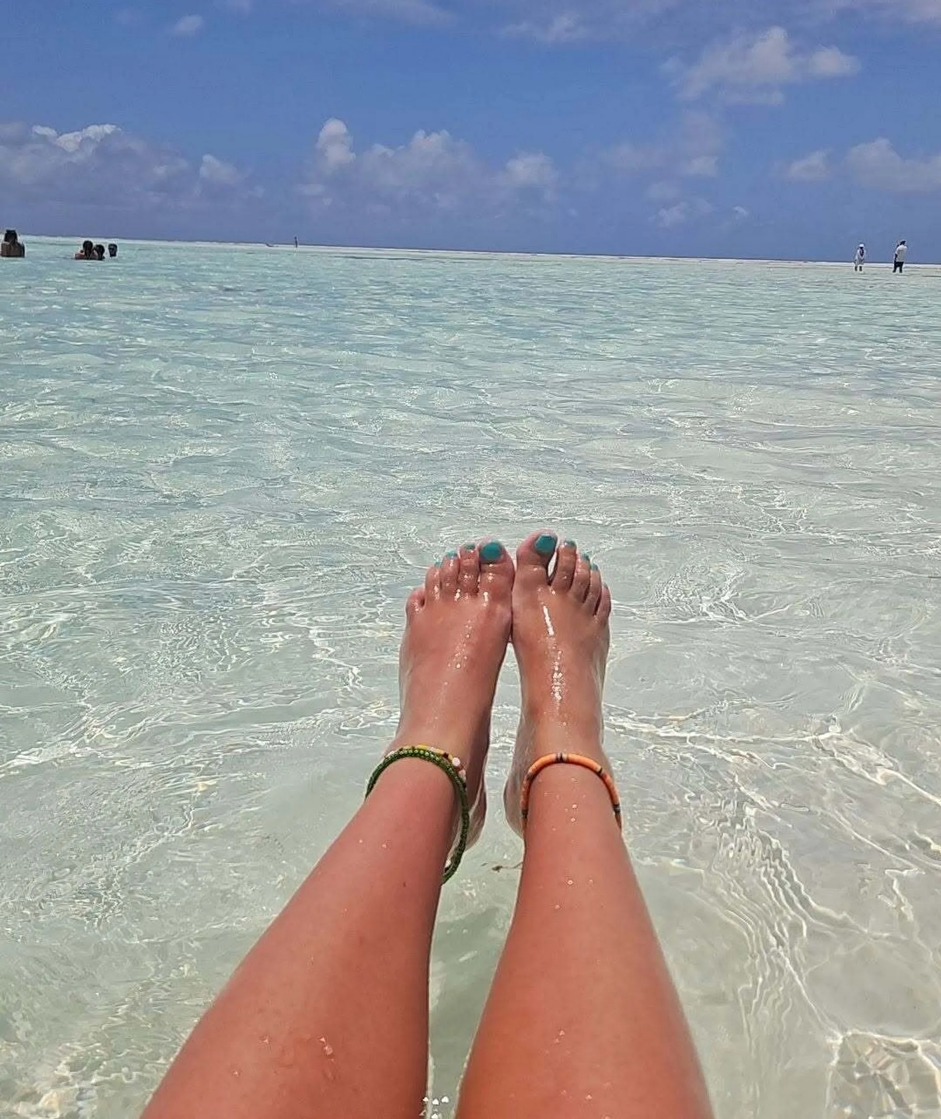 Relaxing in the crystal-clear waters, with anklets adorning sun-kissed legs.