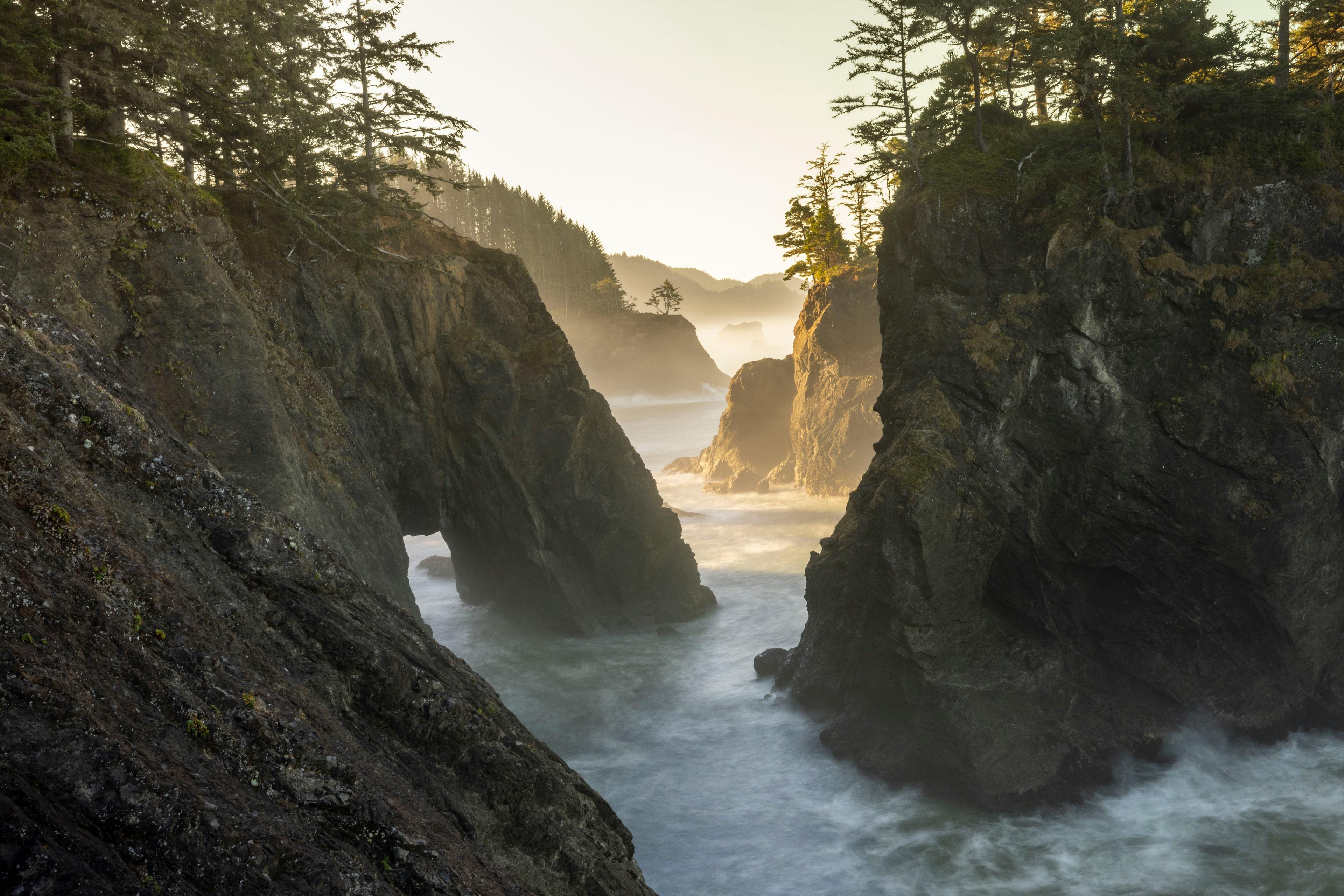 Rugged cliffs and sea stacks are bathed in golden light at Boardman Scenic Corridor in Oregon.