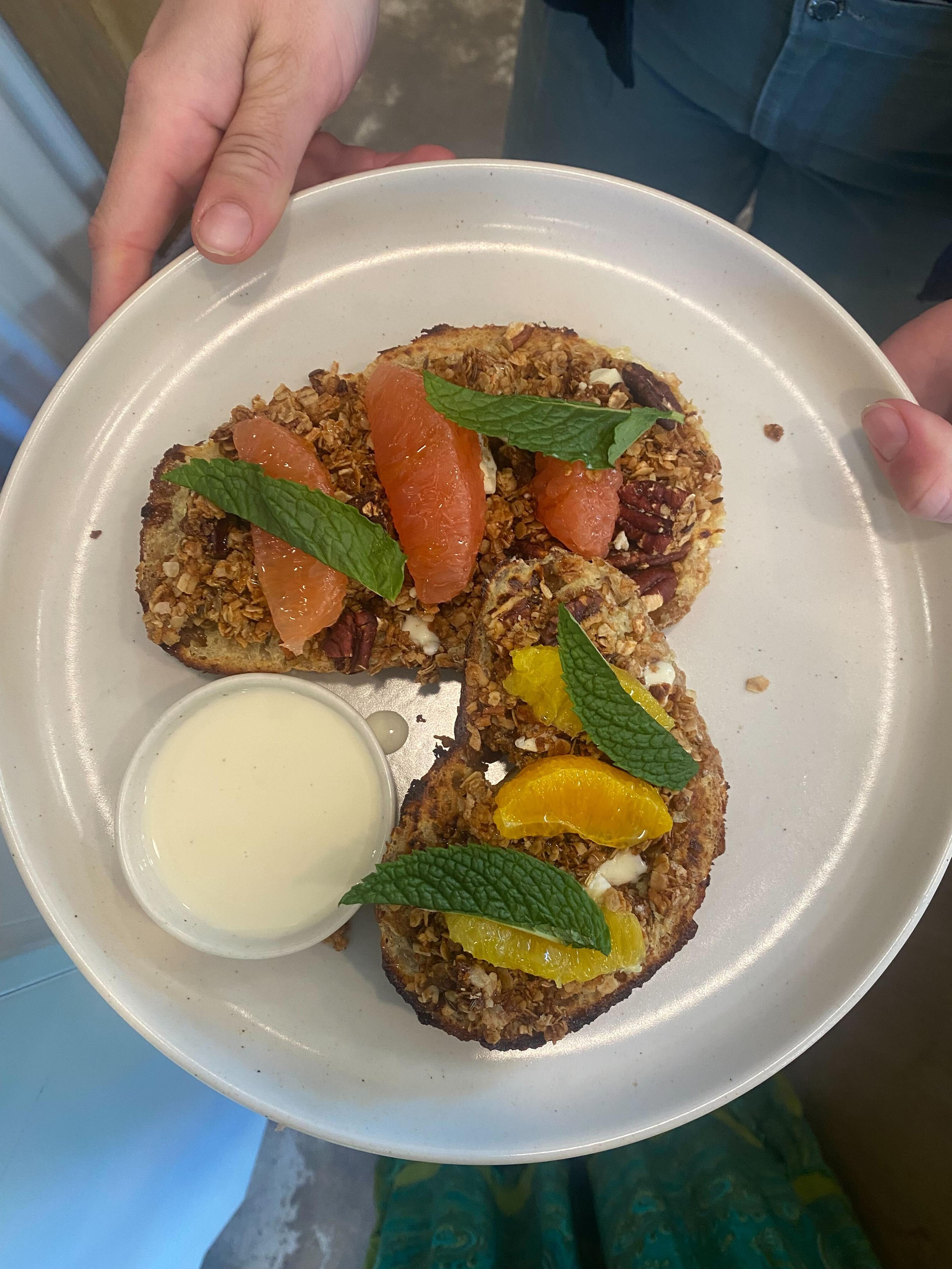 a slab of sourdough coated in vanilla, cardamom, and zesty orange, and stacked with pecan granola, honey, custard, and fruit
