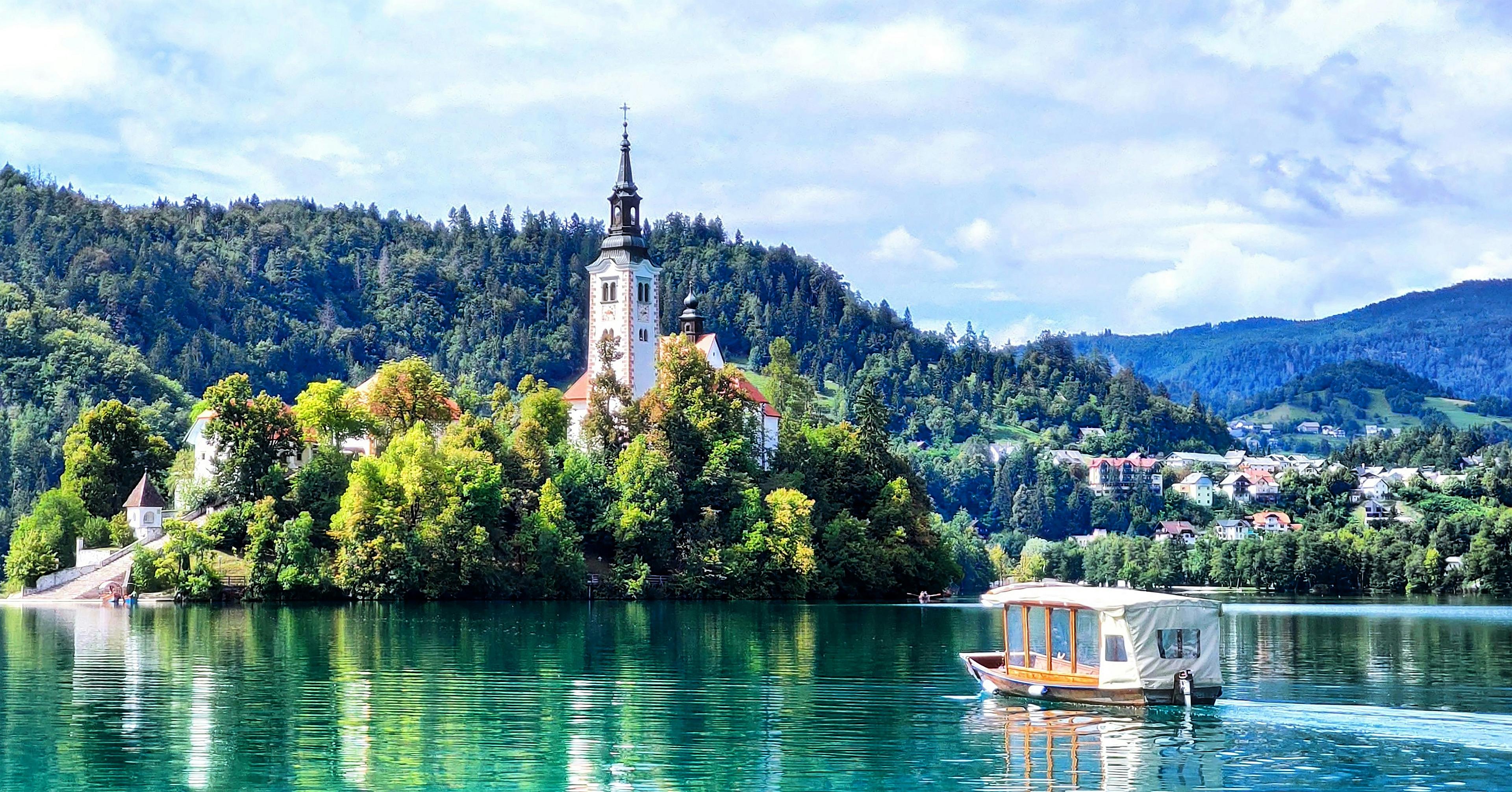 A picturesque scene of Lake Bled in Slovenia, featuring the iconic church on Bled Island surrounded by lush greenery and a tranquil boat on the water.