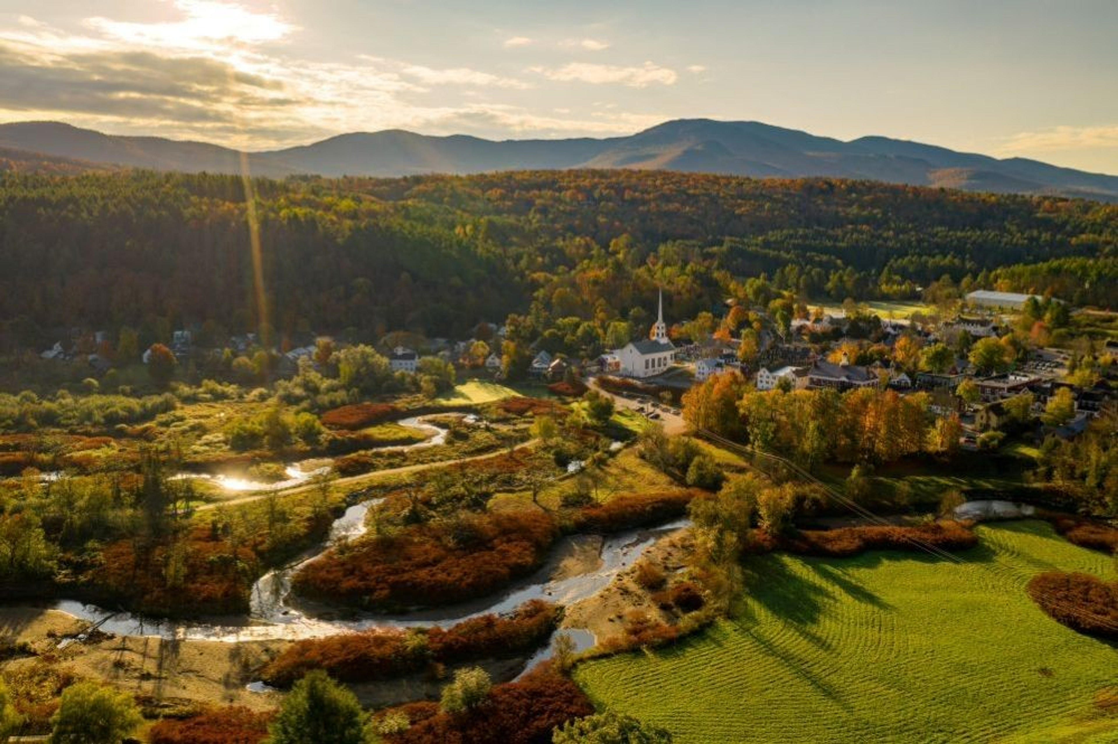 Aerial view of Stowe in Vermont, surrounded by vibrant autumn foliage and mountains.
