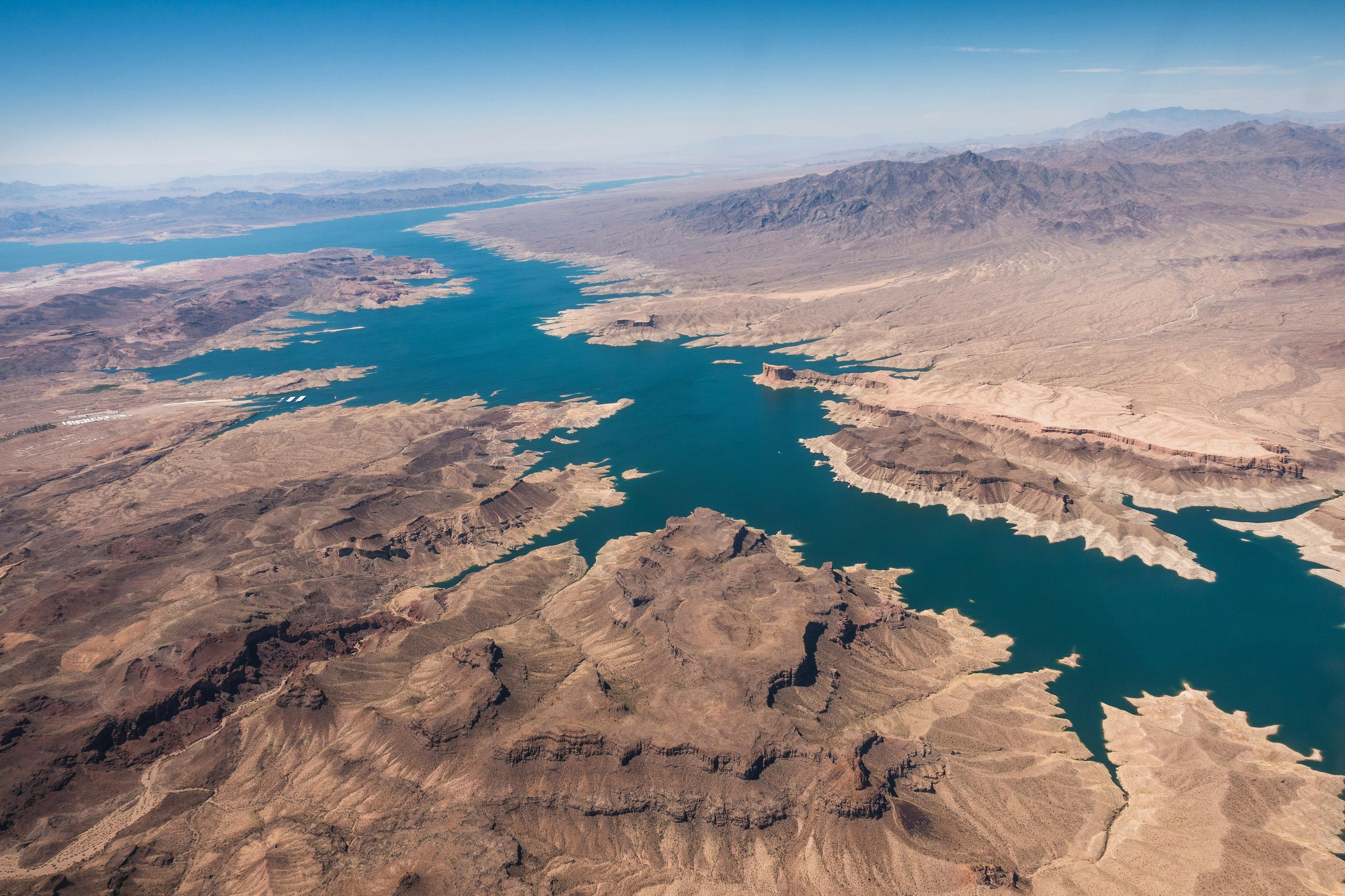 An aerial view captures the rugged landscapes and expansive water of Lake Mead on the Colorado River, bordered by arid terrain.