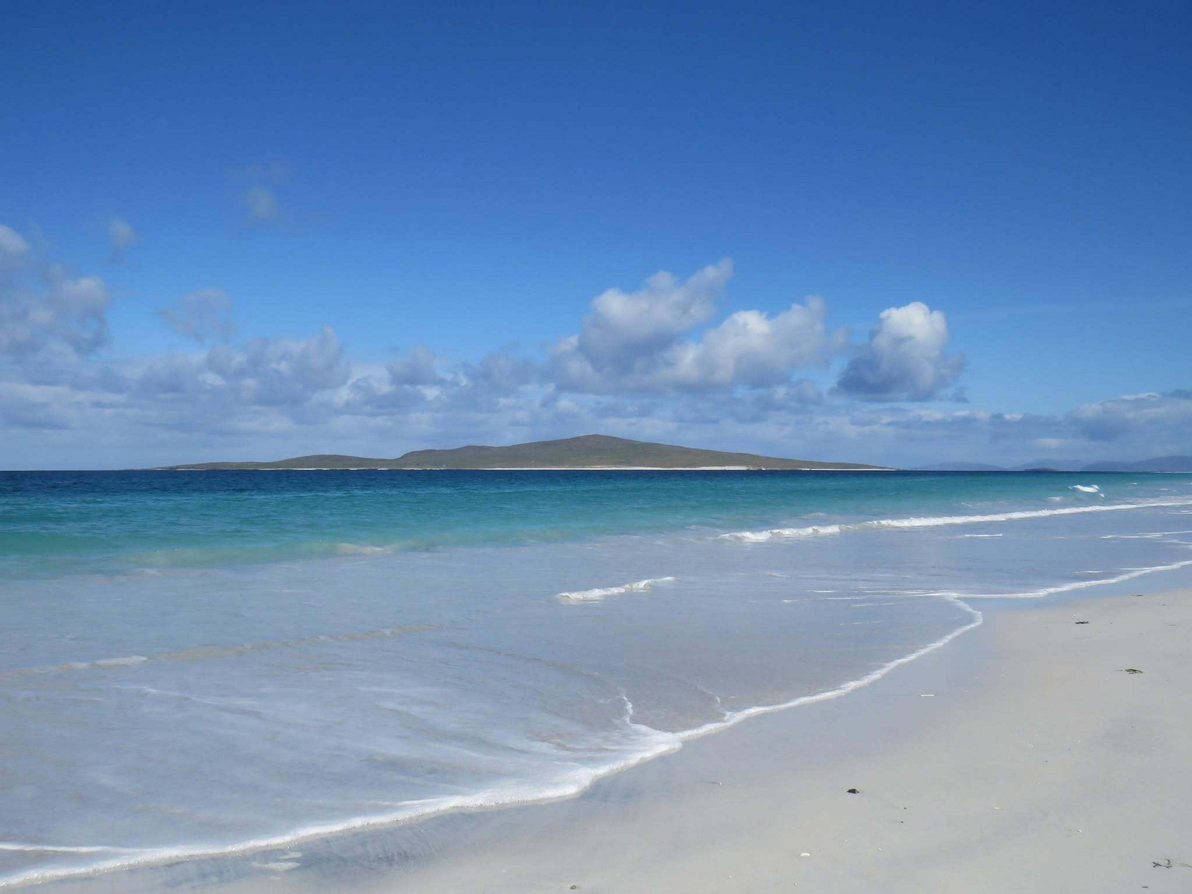 A tranquil beach with white sand and turquoise waters stretches out on Berneray Island in the Outer Hebrides, Scotland.