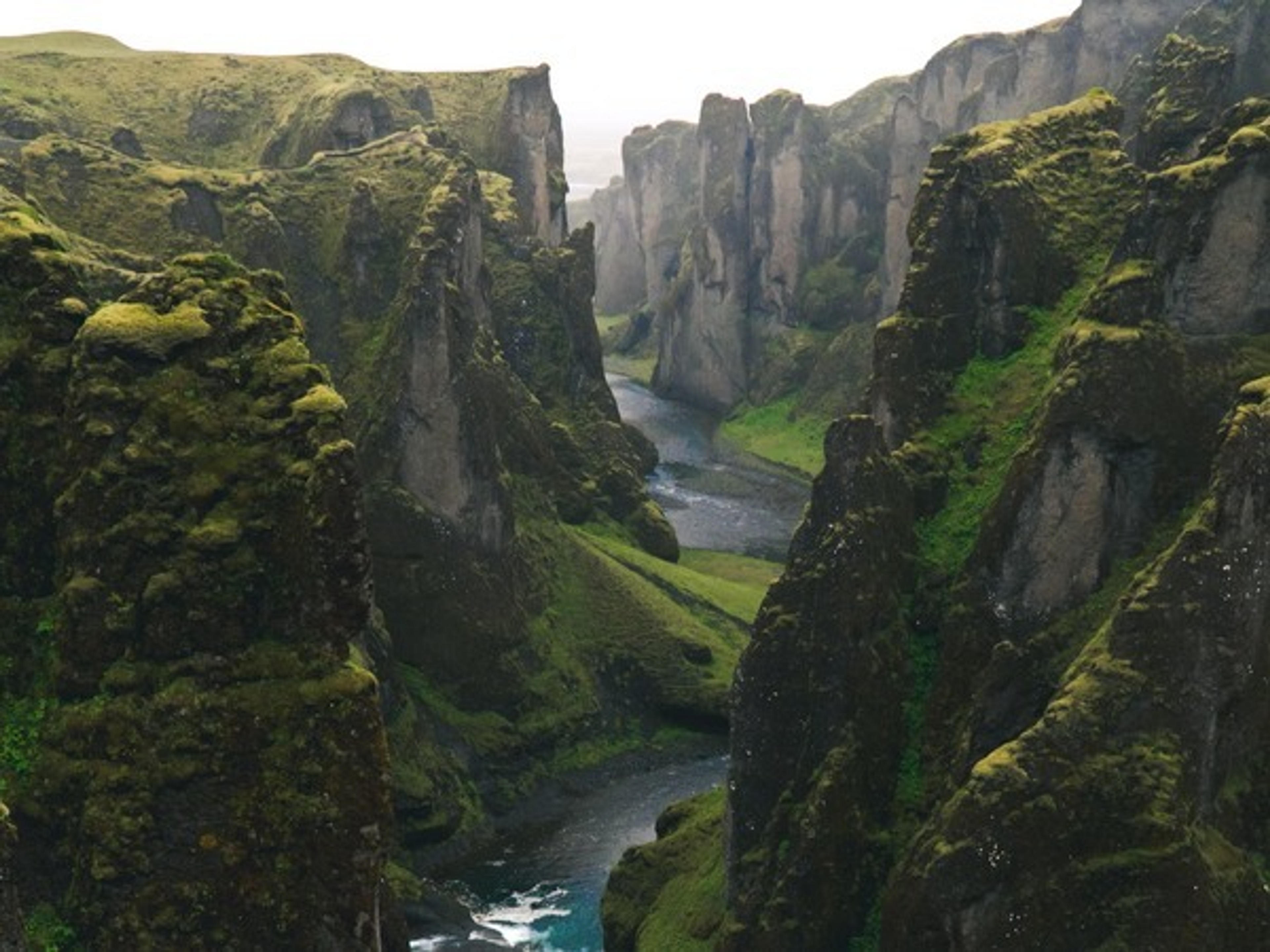 A breathtaking view of Fjaðrárgljúfur canyon in Iceland, with its lush green moss-covered cliffs and meandering river.