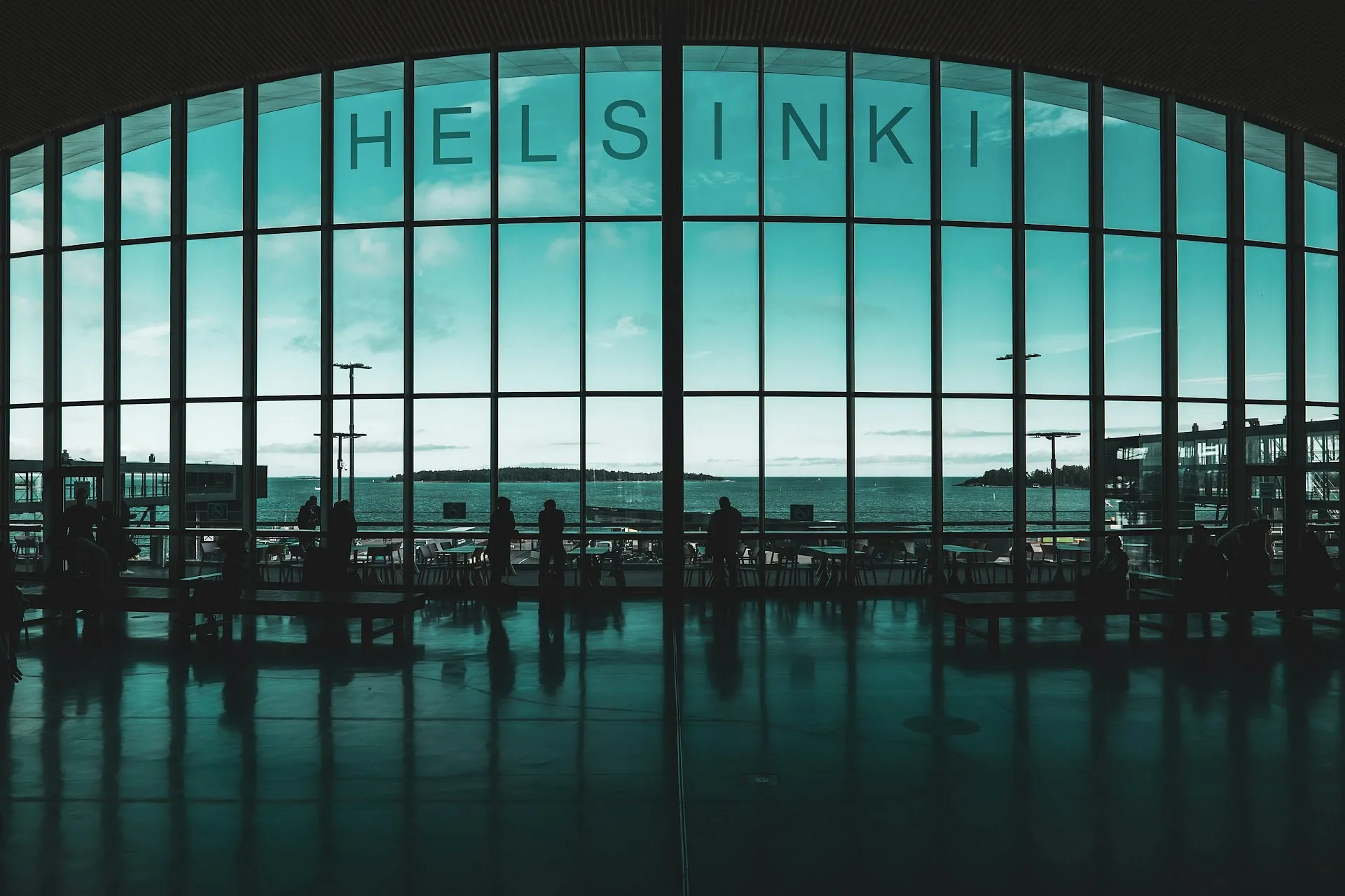 Large glass windows overlooking the sea in Helsinki, Finland, with silhouetted figures inside.